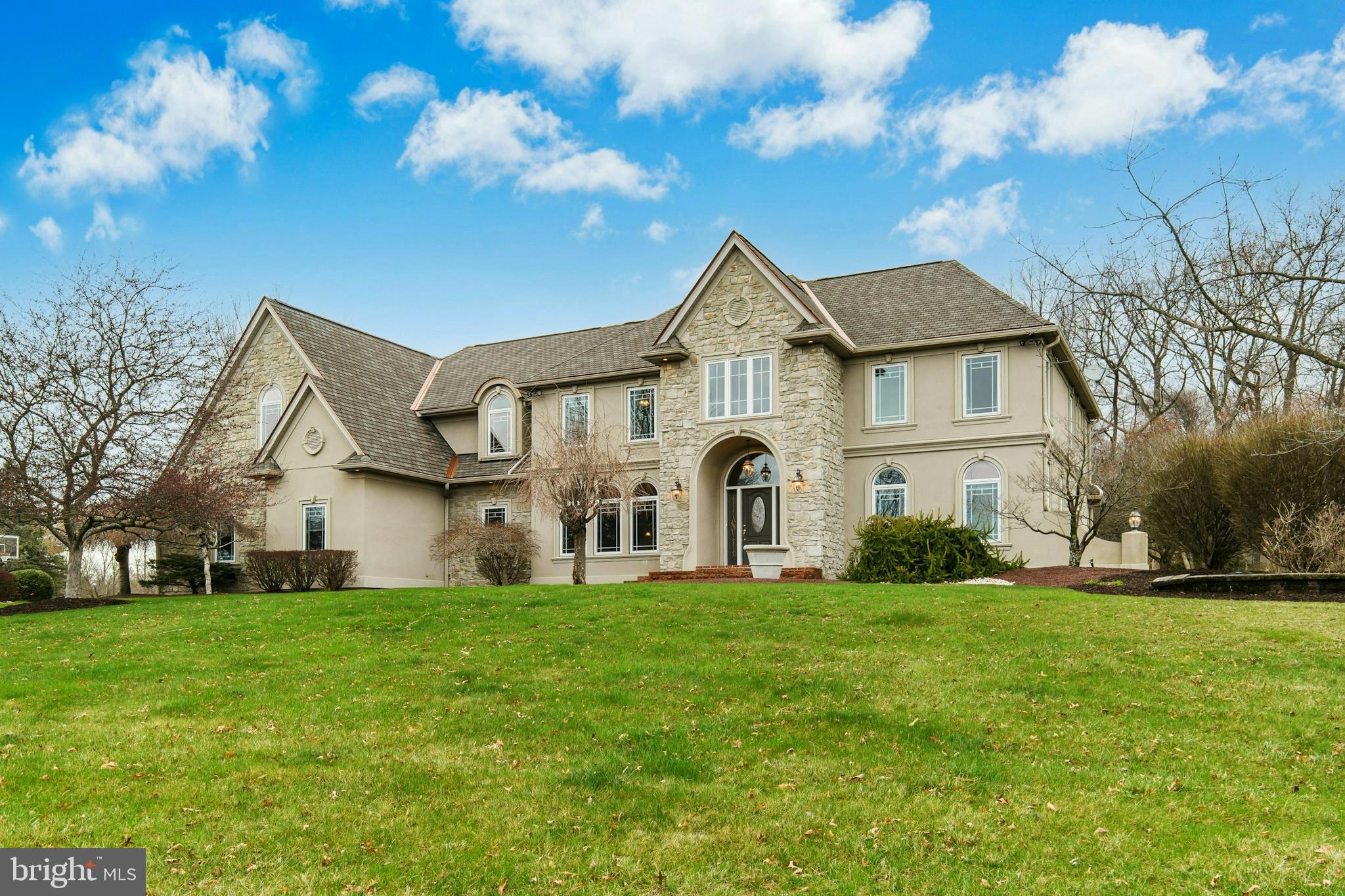 Upon entering Southmoore Manor, it is not surprising that upgrades and finishes abound as it was thoughtfully constructed by a local builder for his personal residence to showcase his high-level of craftsmanship and design. Luxuriously curated and elegantly presented with heated floors, beautiful millwork, archways, new paint, new carpets and designer finishes, the home’s condition is comparable
to new construction while the appointments exceed the craftsmanship available today. The heart of this home is the soaring great room with 20’ tray ceilings and a floor-to-ceiling stone fireplace and dream kitchen, boasting heated floors, granite counters, designer fixtures, high-end appliances and French doors to the patio and inground pool. A first-floor guest suite, living room with fireplace, and bulk pantry are added bonuses. The split staircase with twisted iron balusters leads to a spacious second floor. The primary bedroom is a true sanctuary, featuring a spa-like ensuite with exquisite finishes, a jetted tub, oversized shower, and massive walk-in closet. Four more notably large bedrooms with walk-in closets and a roomy and thoughtfully designed laundry room complete this level. An expansive lower level offers space for play and relaxation for all as it encompasses a recreation room, media room,
exercise room, and workshop. The 1.3 acre cul-de-sac lot is enviable, with patios, saltwater inground pool, mature trees and upgraded landscaping. The sought-after neighborhood has a nearby 18-hole golf course and easy access to the Lehigh Valley and points North.