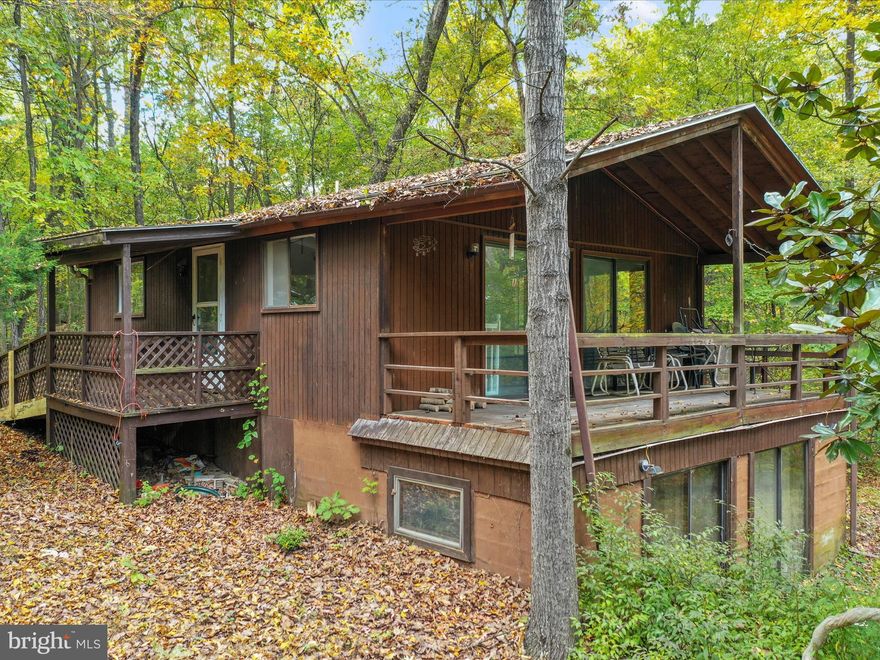 Embrace the rustic charm and endless possibilities that await in this secluded cabin in the woods! Nestled on over 5 acres, offering the perfect blend of tranquility and adventure. Featuring 2 bedrooms, 1.5 baths. The main level offers an open floor plan, living room with a wood-burning fireplace, dining area, and kitchen with ample cabinetry and table space. Step outside onto the expansive deck, where you can unwind and soak in the serene sounds of nature. Take the spiral staircase down to the basement-level bedroom, half bath, and walkout level to the outdoors. This property is being sold as-is, allowing you to add your personal touch and create the perfect woodland escape. Located just a short distance from Cherry Run public boat access to the Potomac River, ideal for outdoor enthusiasts. Don't miss your chance to make this your own piece of paradise!
