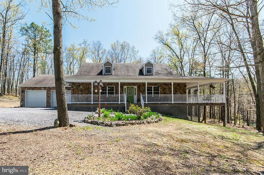 Lovely custom stone and vinyl cape cod on 9+ unrestricted wooded acres with a stocked pond.  Full daylight basement with bath could be made into an in-law suite.  Hardwood floors throughout the main level.  Floor to ceiling stone fireplace in the great room, sun room with ceramic tile floor, master BR walks out to screened porch. Wrap porch 8 miles to downtown Berkeley Springs. Private