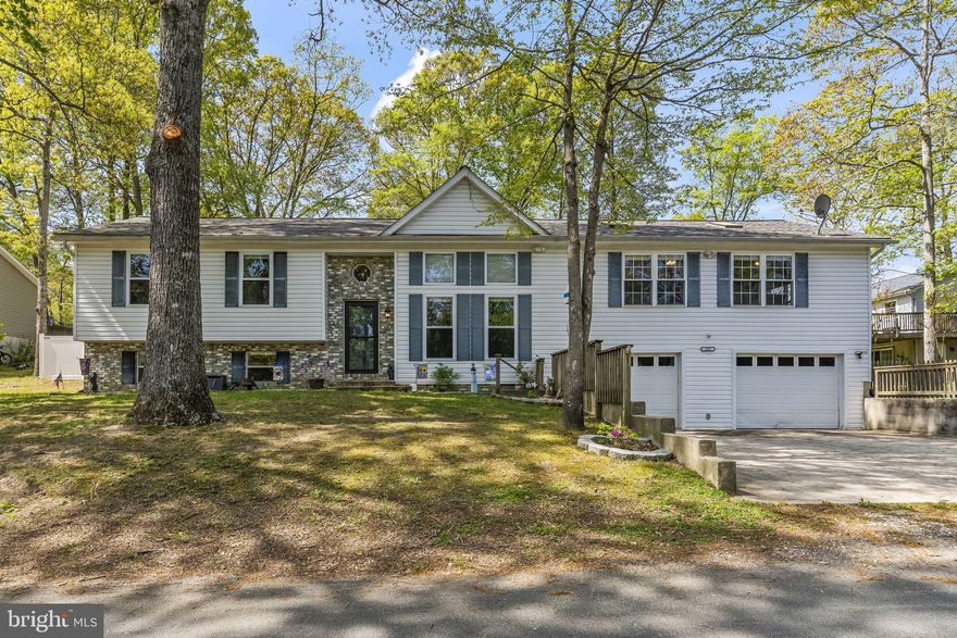 Almost 3,000 finished square feet of living space, oversized two car garage plus large fenced lot close to the the town square community entrance -walkable to shopping restaurants and everyday conveniences!  You will love the unique floor plan and custom finishes that begin as soon as you step into the soaring living room.  Gorgeous custom railings continue the open concept allowing full visibility to the kitchen area  that overlooks the first level.   Spacious kitchen offers updated stainless appliances, built in storage and open space.  Formal dining with built in buffet and storage leads to the huge family room and a private bedroom.  Primary suite includes a beautifully updated full bath.  This level has a total of four bedrooms and two baths.  Lower level gives even more space with recreation room, laundry, plenty of storage and a bonus room that connects you to the oversized garage and workshop area with walk up to the incredible fully fenced back yard which is perfect for entertaining with a 24 by 11 deck with pergola, 28 by 19 patio with second pergola, multiple storage sheds and more!  Community access to two sandy beaches on the Chesapeake Bay, or enjoy access to Lake.  Easy drive to Solomons Island, community parks and recreation areas, and short commute to PAX NAVAIR.  Check out the floor plans included to see just how spacious this custom home truly is!