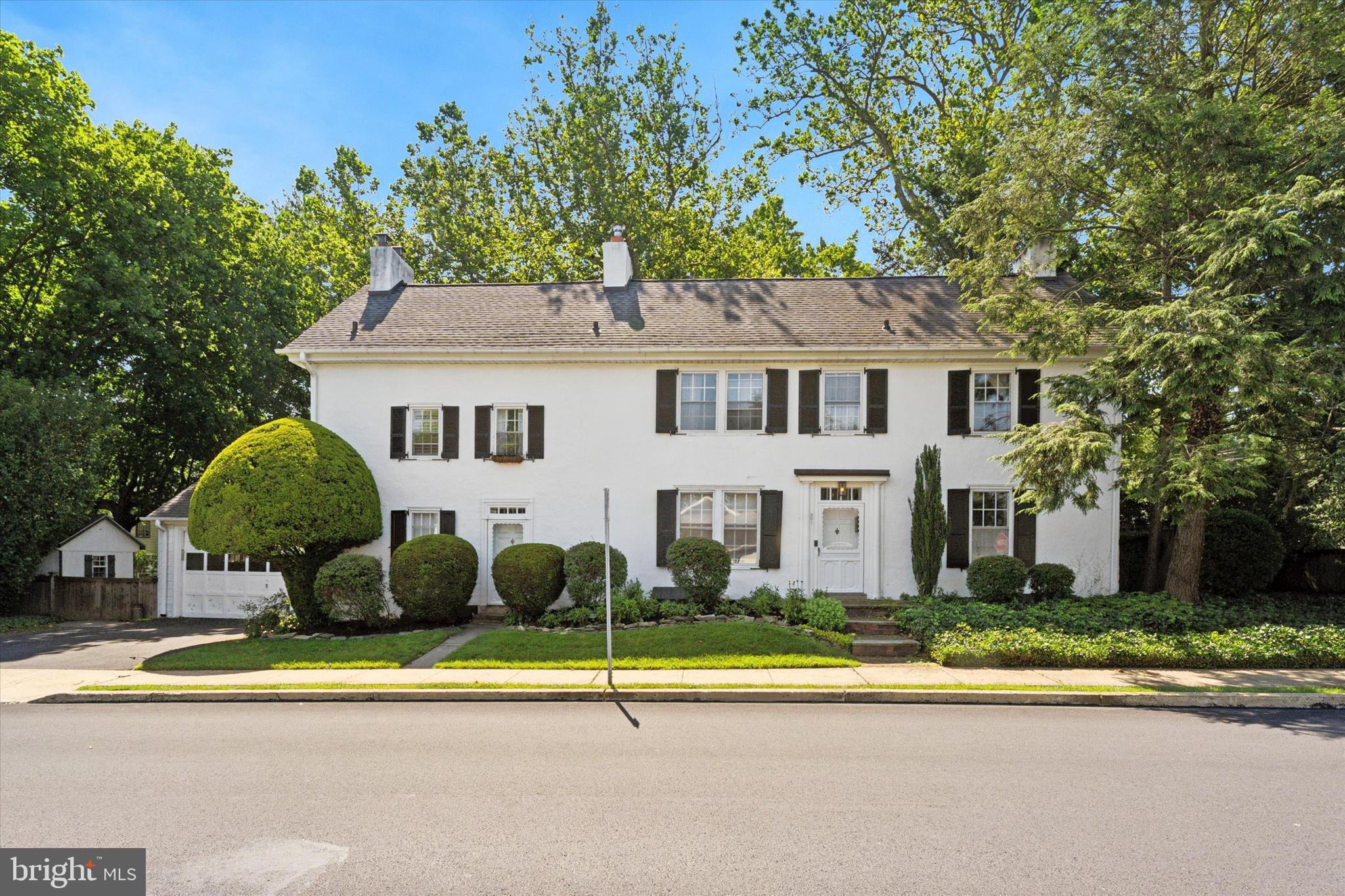 Step into timeless character and effortless comfort in this meticulously restored 4-bedroom, 3.5-bath Colonial residence, originally constructed in 1758 and thoughtfully updated from 2007 through 2018. Nestled on a picturesque, fenced-in corner lot measuring over a third of an acre, this home is a standout blend of historic architecture and modern amenities — including central air conditioning.
A stucco-over-stone façade and professionally landscaped grounds set the tone, while a two-car garage and welcoming entrance along Division Avenue provide everyday convenience. Recognized as a historic resource by the Upper Moreland Historical Society, this residence reflects its origins as part of a larger farm predating the surrounding neighborhood.
Inside, 20-inch thick stone walls, deep windowsills, wide-plank hardwood floors, and handcrafted millwork deliver authentic period charm. A total of six wood-burning fireplaces are located throughout the home, beginning in the warm and inviting living room. The formal dining room offers built-in shelving, a pantry closet, and another working hearth.
The chef’s kitchen is both functional and stylish, featuring granite countertops, a tile floor, a Wolf range with stainless hood, soft-close cabinetry, a double farmhouse sink, Asko dishwasher, and stainless refrigerator. Just off the kitchen, a sunlit breakfast room with dual exits to the exterior flows naturally into a cozy family room adorned with exposed beams, custom built-ins, and yet another fireplace.
Two staircases — one in the front and a more discreet option off the family room — lead to the second level. The primary suite includes a working fireplace, ample closet space, and a spa-inspired bathroom with marble tile, a soaking tub/shower combo, and pedestal sink. Two additional bedrooms (each with fireplaces and ample storage) share a hall bath renovated with period-appropriate fixtures and finishes. A connecting bonus room offers flexibility as a home office, sitting room, or guest space.
On the third floor, discover an additional private office or bedroom, a game or playroom with dormer windows and cedar closet, and a fourth bedroom with en-suite bath — ideal for guests or extended family.
The lower level includes laundry facilities, a deep farm sink, and access to the backyard through Bilco doors. Outdoor living is just as special, with a two-tiered brick patio, mature trees offering shade and privacy, and a vegetable garden ready for summer harvests.
Key system upgrades include a newer roof, newer gas furnace, updated 200-amp electrical service, central air, and restored windows. Located just minutes from regional rail, parks, Willow Grove Mall, the PA Turnpike, and top-rated Upper Moreland schools, this exceptional home offers rare character with modern functionality.
