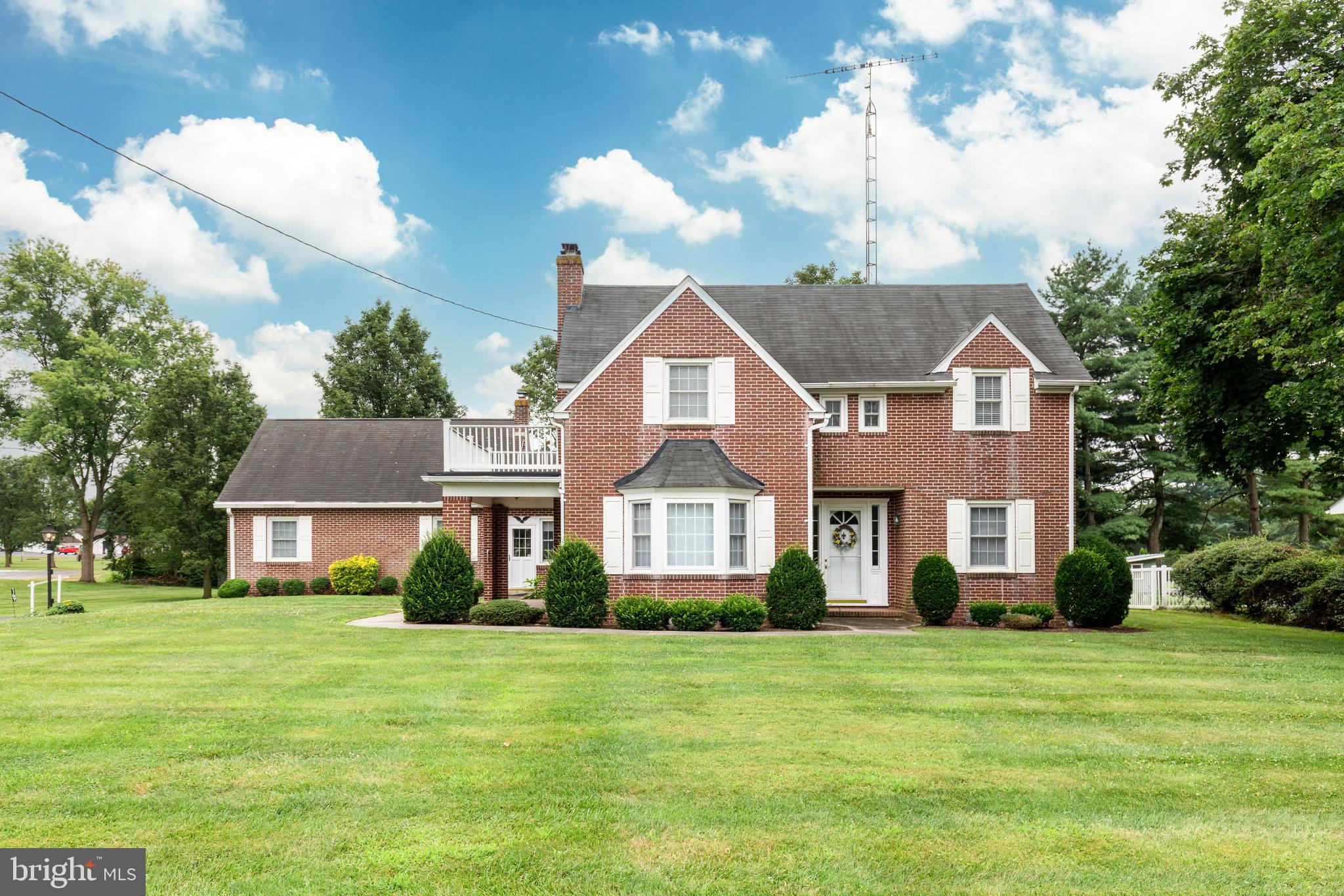 Timeless Charm Meets Modern Comfort in This All-Brick Beauty! Step into this character-filled home featuring gleaming hardwood floors throughout and a warm, inviting living room with a classic brick fireplace, a picturesque bow window, and custom built-in shelving. Enjoy meals in the formal dining room or cook up memories in the spacious country kitchen. A bright and airy sunroom addition offers year-round enjoyment, while a main level bedroom with built-ins provides versatility for guests or home office needs. Upstairs, the expansive primary bedroom boasts a private balcony and an impressive five closets. Two additional generously sized bedrooms, full updated bathroom and a whole-house fan complete the upper level. The unfinished walkout basement offers endless potential for additional living space or storage. An oversized attached two-car garage includes a half bath and a floored upper-level storage area. Outdoor living is a breeze with covered front and side porches, a rear concrete patio, a level yard perfect for play or gardening, and a handy storage shed. A rare find with space, character, and functionality—schedule your showing today!