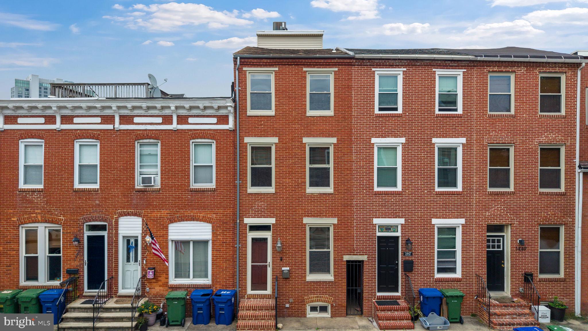 Tucked away on a tree‑lined block in historic Locust Point, this beautifully renovated rowhome blends classic Baltimore charm with modern convenience. Behind the handsome brick façade you’ll find an open‑concept main level with rich hardwood floors, exposed brick accent walls and a sleek, open‑riser staircase. The living and dining areas flow effortlessly into a renovated chef’s kitchen featuring warm wood cabinetry, granite countertops, stainless‑steel appliances and a tile backsplash. Large glass doors lead to a fenced patio with stone pavers, string lights and bamboo screening—perfect for outdoor dining and entertaining. The upper levels host three spacious bedrooms, three full baths and two powder rooms. The owner’s suite is spacious and provides a walk‑in closet and an en-suite bathroom with a large walk-in tiled shower. Additional bedrooms offer generous closet space, hardwood or carpeted floors, large windows and exposed brick or ductwork that add industrial flair. A second full bath features chic tile work, jacuzzi tub and plenty of storage space. There's also an upper‑level wet bar/entertaining nook for easy rooftop access, half bath and bonus room that is perfect for a home office, second living room or guest area. The finished basement expands the living area with tiled floors, a half bath and space for a home gym, office or guest suite. The crawlspace area is perfect for storage and is dry and runs the entire back portion of the house. Laundry is conveniently located on the bedroom level, and there’s a mechanical room for extra storage. Both HVAC systems have been recently updated for peace of mind and comfort. Crowning the home is a sprawling rooftop deck—an urban oasis with panoramic views of the Baltimore skyline, harbor and neighborhood rooftops. Whether you’re enjoying morning coffee or hosting sunset gatherings, this space offers a front‑row seat to everything Locust Point has to offer. Located just blocks from the waterfront, Fort McHenry, community parks and the shops and restaurants of McHenry Row, this property provides easy access to I‑95, downtown and Federal Hill while retaining a quiet neighborhood feel. With its blend of historic character, modern updates and prime location, this home is a must‑see for anyone seeking the best of city living.