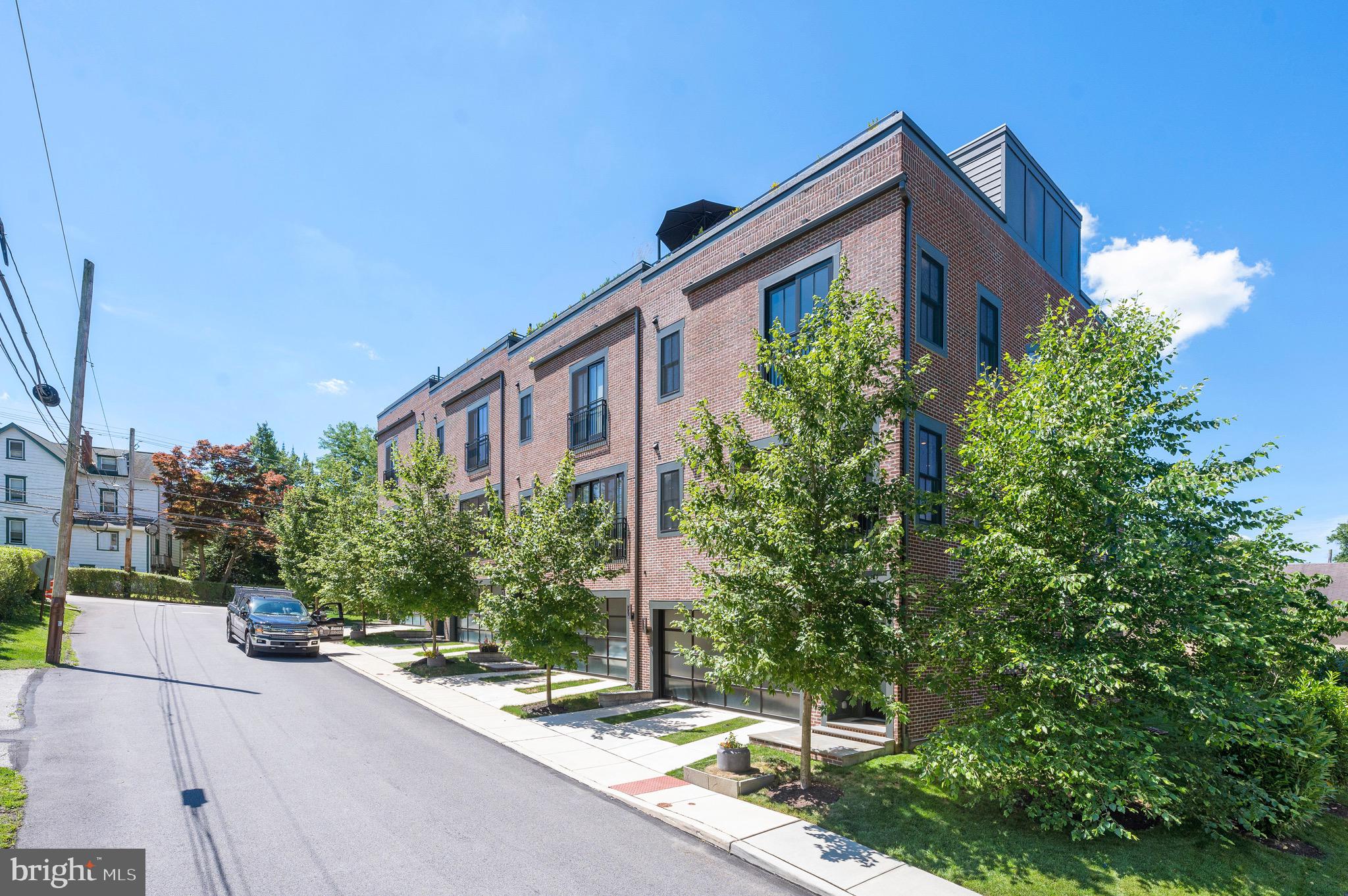 The townhomes at Plant & Willow are inspired by the humble beginnings of industrial buildings: former factories and warehouses with their worn flooring, distressed walls and original pipes have always been functional, only recently becoming iconic. Plant & Willow embraces the architectural style known as "Industrial Chic" which glamorizes elements such as large windows, high ceilings, exposed brick and post and beam details. 207 Willow Avenue offers a 3-story end unit townhouse with spectacular views of the surrounding area from its large windows and is elevator-ready. Cool, chic, sleek, sexy can all be used to describe this one-of-a kind townhome. Pull up to the property and immediately you are wowed by the unique brick facade and sleek garage doors. Enter the front door and prepare to be wowed on every floor from the floating staircase, the large windows, the incredible views, the impeccable finish choices and upgraded lighting. The first level features inside access from the garage with mounted organizer and a storage/utility closet. The main level was upgraded with tile floors from the concrete floors the builder provided for a sleek clean look and boasts multiple closets. This floor has a spacious ensuite bedroom with lots of natural light from the large windows, sensational overhead light, attached tasteful shelving and two closets. The bathroom has a suspended vanity and stall shower with wavy glass subway tiles. Up one level is the approximately 20’ wide main living level which creates a fantastic loft-like openness from the kitchen, dining and living rooms. The gorgeous Industrial Chic kitchen with large island with honed black granite countertops features pull-out drawers, lift-up cabinets, open shelves and a walk-in pantry for maximum storage and design appeal. The high-end appliance package includes Thermador range top and oven, Kitchenaid French-door refrigerator and Bosch dishwasher. The living room has an exposed brick accent wall, a sleek gas fireplace with TV mount above, and a decorative wine rack wall and stunning views of the surrounding treetops from the large windows. A powder room with pedestal sink and sleek lighting fixture completes this floor. This main level is spacious for entertaining or living your best daily life. The next level up has hardwoods throughout like the main floor and boasts the 2nd bedroom, hall bathroom, laundry and the primary suite. The second bedroom is very spacious and boasts large windows, a sleek built-in shelving feature and sleek track lighting. The hall bathroom has a suspended single vanity, a large window and a tub/shower with wavy glass subway tiles. The laundry room is large with ample room for baskets and storage. The primary suite features large windows with tree-top views and stylish overhead and hanging bedside table lights, two walk-in closets, and a large primary bathroom. The sophisticated primary bathroom features a suspended double vanity, toilet and oversized tiled shower with multiple shower heads, multiple shower jets and a hand spray. Up one more flight of stairs via the extremely inviting open staircase to the find the roof top deck. The roof deck was completed with wooden decking squares, planter boxes, accent lighting and direct line natural gas fire pit. Imagine hosting gatherings here to enjoy the evening sunset or watch the local fireworks or just relaxing at the end of the day with a glass of wine, a book and the sound of the birds chirping? What an incredibly unique feature for a home in the Wayne area!! Other special things to know about this home: all closets have custom built-ins, all recessed lighting is controlled by Smart Switches and can be controlled remotely, the property is elevator-ready from the first floor to the roof top pilot house, lighting was upgraded throughout the house, and The Shade Store window treatments were installed on many of the windows. The sellers’ impeccable taste will be your benefit for years to come!