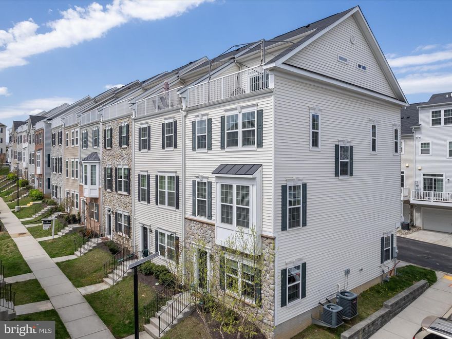 Exquisite and expansive, this four-level end-unit townhome offers four bedrooms, three full bathrooms, and one half bathroom in the desirable Elkridge Crossing community. Designed with refined elegance, each space is filled with natural light and adorned with sophisticated finishes and a neutral palette. The entry level opens to a versatile family room—ideal for a cozy lounge, home office, or recreation area—along with access to the two-car rear garage. A seamless flow defines the main level, where rich hardwood floors, recessed lighting, and thoughtful design details elevate the living experience. Anchored by a custom shiplap accent wall, the living room invites comfort and style, while the gourmet kitchen impresses with quartz countertops, a spacious center island with pendant lighting, 42” cabinetry with undermount lights, a tile backsplash and pantry. The stainless steel appliances include a gas cooktop with a range hood, a wall oven and a microwave that also functions as a second oven, along with a new dishwasher. The adjacent dining area opens to a balcony—perfect for grilling or dining al fresco. Upstairs, the primary bedroom suite features a walk-in closet and an ensuite bath with a dual-sink vanity, separate toilet room, and a large frameless walk-in shower with a bench. Down the hall are two additional bedrooms that share a full bathroom with a tub shower. A convenient laundry closet with new washer and dryer completes this level. The top floor is a private retreat, offering a fourth bedroom with its own walk-in closet, luxurious ensuite bathroom, and rooftop balcony—an ideal setting for relaxing summer evenings. Located in Howard County with easy access to major commuter routes and a wide array of dining, shopping, and entertainment options, this stunning home offers both luxury and convenience.