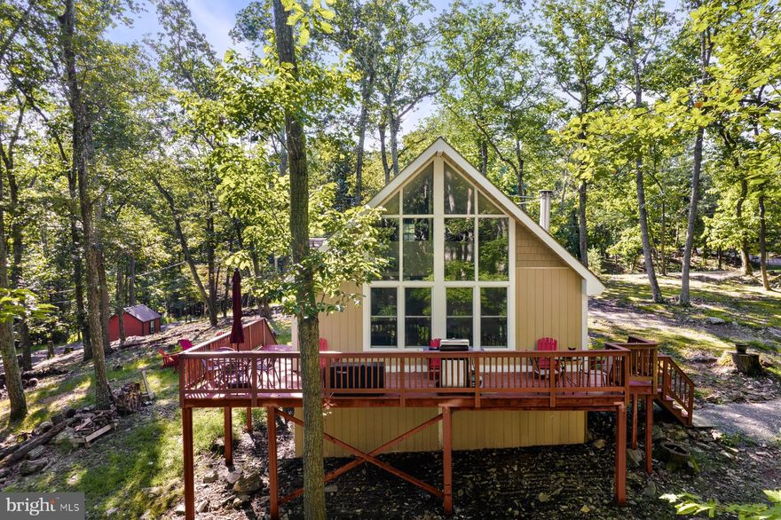 Completely remodeled 2-bedroom (plus loft), 1-bath chalet in The Wood Resort – the perfect blend of modern comfort and natural beauty with tall ceilings, floor-to-ceiling windows, luxury vinyl plank flooring.  The updated kitchen features sleek shaker cabinets and modern stainless steel appliances. The wraparound deck provides ample outdoor space for relaxing or entertaining, while the open, cleared yard is perfect for outdoor activities. Professionally designed with all new furniture, modern decor, and hot tub. Seller spent over $46,000 upgrading the property.  As a vacation rental, it generates $50,000 per year (over $150k over the past 30 months!), and can come with an existing property manager and cleaner. This chalet is located in the Woods Resort and has a Class B membership with access to a private community with an 18-hole golf course, indoor & outdoor swimming pools, gym, tennis & basketball courts, & more.  Hot tub and furniture optional, available for purchase.  See seller docs for a summary of rental history and financials.  $1,000 buyer credit if you continue using the same property manager.  Perfect vacation home or investment property!