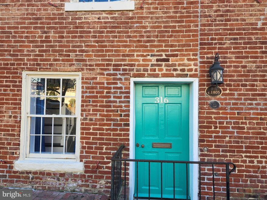 Unique layout and old-world character are what you will find in this rental at 316 Princess Anne Street, in downtown Fredericksburg. You won’t want to miss this almost 2200 square foot home that was built in 1805 with style and charm but has been brought modern with central heat and air conditioning. This home is comprised of three different levels, and the third level is split between the right side and left side of the home, making ideal space for separation. The main level starts with a grand foyer where you can settle in the living room or dining room. The living room has a gorgeous fireplace (decoration only), and the dining room has tons of storage. The quaint kitchen is just a step down from the dining room and with ample room for cooking. Another gorgeous fireplace (decoration only) adds even more character to the kitchen which has stunning wood beams on the ceiling. This level also includes a powder room for convenience and lovely rustic pine floors. Heading upstairs to the second level, you will find a generous size laundry room, full bathroom, a large room that can be used as a bedroom or sitting room, and entrance to the newly finished balcony. There are also two sets of stairs that lead you to each of the upper levels, one of which has a beautiful free-standing bathtub. There are so many options in this home with nooks and crannies for all your storage needs.  The back yard feels like a courtyard and is fenced for your privacy and seclusion. There is a dedicated parking space that can hold 2 cars and city parking by permit. Pets are allowed on a case-by-case basis.