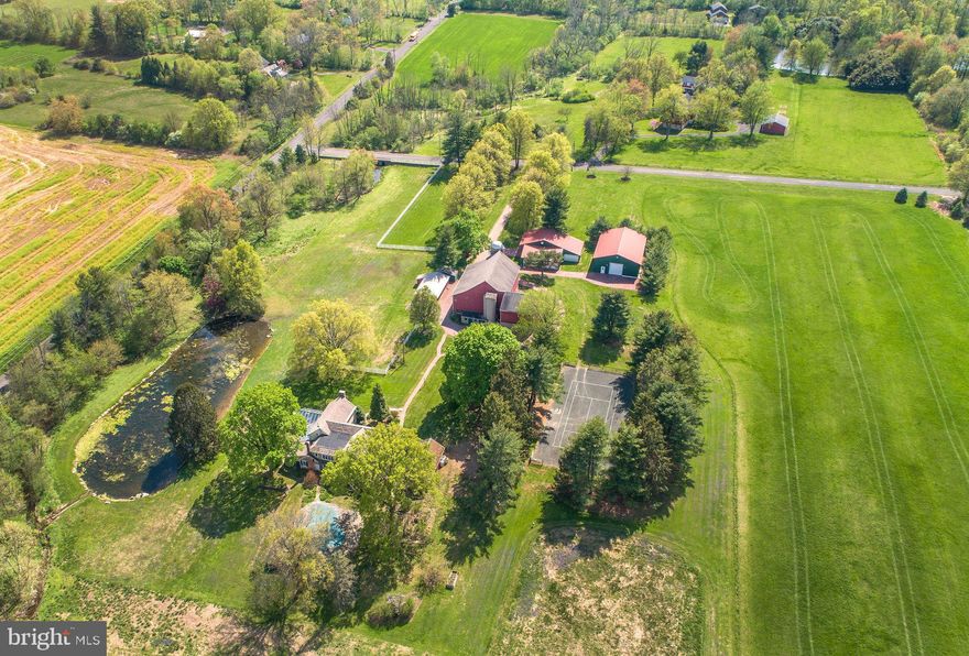 Windy Hill Farm has been in the same family for over 60 years. This 30-acre estate is the quintessential Bucks County gentleman's farm. Enter thru a tree lined drive framed with mature Pin Oaks, past a classic stone and frame bank barn complete with the original silos from its dairy farm roots. The large pole barns are ideal for a classic car collection or great for farm equipment and storage. A deep green corn crib is an iconic reminder of the heritage of this stunning property. At the end of the drive a beautiful vintage stone and brick four-bedroom farmhouse with conservatory and original touches awaits your imagination as a clean canvas. The home is ideally situated overlooking a sprawling pond with a stone cascading waterfall, inground pool, and tennis court. Mature specimen trees dot the property creating an oasis of total privacy for outdoor entertaining. Create a family compound with the assurance that no development will ever spoil this hidden gem tucked away on a quiet country road only ten minutes from Doylestown. This is truly a special property that awaits your inspiration and guidance as its new steward.
