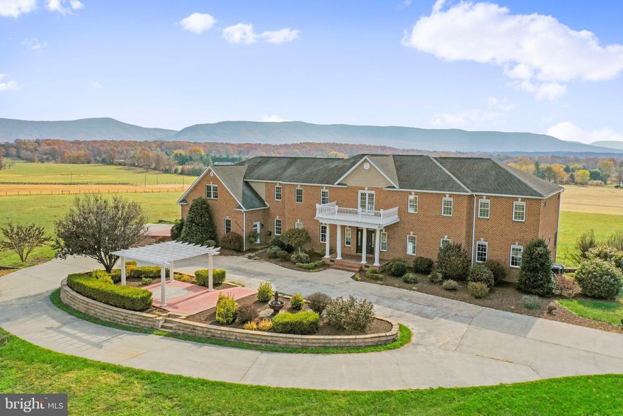Check out this luxurious brick manor for sale!  There is no shortage of space inside or outside this stunning 5272 sq ft home on over 10 acres!  This property offers panoramic mountain views that will take your breath away. Inside, you'll find beautiful white and red oak hardwood floors throughout, adding warmth and character to every room. The custom kitchen is a chef's dream, complete with granite countertops, a 6 burner gas range and range hood, an oversized island with sink, and a built-in wine cooler. The breakfast nook and sunroom are flooded with natural light, while the separate dining room and living room with gas fireplace provide plenty of space for entertaining. The main level primary suite boasts a walk-in tile shower with rain shower head, granite dual vanities, and oversized walk-in dual closet. Upstairs, you'll find four spacious bedrooms, each with their own bathroom and walk-in closet, as well as a huge rec room and additional family room with built-in wet bar. With a circular concrete driveway and three-bay attached garage on the main level, and a fourth bay on the lower level, there's plenty of room for your vehicles and toys. The unfinished basement provides even more possibilities, including a start to a theater/media room and rough-in plumbing for an extra bath. And if you ever need to move between floors, there's even an elevator shaft ready for installation. Convenient Location - this home is just minutes away from schools, I-81, and a plethora of delightful wineries and breweries.  It's surrounded by natural beauty and endless recreational possibilities - less than 10 miles to  Seven Bends State Park, the Shenandoah River, and George Washington National Forest for where you can immerse yourself in scenic hiking and biking trails, refreshing swimming spots, and tranquil fishing/boating areas.  Don't miss your chance to make this your dream home!  Schedule your private tour today!
