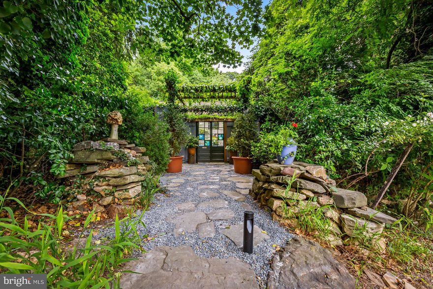 Although this house looks like a miraculous extension of the wooded hill beneath which it hides, it was only in 2003 when Henry Johnson, renowned architectural interior designer, completed construction on his personal home, a single-level masterpiece amongst a collection of gardens and courtyards. The Fieldhouse.

Two sculpted piles of carefully stacked stone form a gateway as a bluestone approach spreads beneath a canopy of the same mature trees that keep this house secret. This entry arbor opens into a forecourt and the bluestone continues up to the front steps where a handcrafted, 200-year-old door opens into the modern elegance of minimalist architecture and the warmth of its creator’s character. 

Three steps into the house, standing in the Library Foyer, beside the impeccable grid of a floor-to-ceiling bookcases running the full length of the entry hall, one finds themselves at the crux of an “L’d” intersection; to the right: the living space, straight ahead: the sleeping quarters. 

The living space. A wall of windows, five pieces of plate glass 78” x 60” lead to a living room unlike any other in Baltimore. Centered on the East wall, a fireplace sits upon a French limestone hearth that spans the width of the room, impossibly hovering above the hardwood floors (a mixture of 300-year-old English Oak and Chestnut). The lush and layered garden view, the perfect proportions and the flawless execution of masterful design, have distracted from the fact that one is also standing in the kitchen. The sink and the cooktop practically vanish into the limestone countertops, the discrete and paneled appliances are hidden in plain sight. Beyond the kitchen, two corridors of 9’ panels hide ample storage: pantries, laundry, closet space, and a half bath. True to the minimalist simplicity, there are no visible hinges or hardware throughout the house. 

The sleeping quarters. From the Library Hall, one finds the suite: a bedroom that opens onto another private courtyard, a dressing room, from which a rear porch enjoys overgrown seclusion, and a full bathroom with the perfect simplicity of a walk-in shower beneath an illuminated ceiling while the tiled geometry becomes infinite within the mirror.

Within the “L” of the primary house, a patio of 19th century marble sits beneath a vast trellis of English ivy and trumpet vine, this is a space for morning coffee and dinner parties, the quiet gathering of a few or the crowded collection of many. Beyond the trellis is the Sundial Garden, another chamber in this campus of gardens; just down the path, the true surprise is found…

The log cabin. Built in 1743 in Charleston, South Carolina, the cabin was disassembled and trucked up to Baltimore where it was reconstructed upon a new foundation and the modern conveniences of air conditioning and running water were added. Through the front door, the modernity of the primary house finds perfect balance with this nearly 300-year-old structure. A living room opens on to a screened porch, a modest, and appropriately rustic bathroom has been retrofitted beneath the stairs that lead to the 2nd floor bedroom above. The cabin’s possibilities are endless: office, guest house, additional living space, or simply a second bedroom.
The Field House enjoys convenient access to Lake Avenue, Northern Parkway and Falls Road.
NOTE: Of the listed rooms, The Den, 2nd Bedroom and 2nd Full Bath are IN THE CABIN. The square footage might not reflect the cabin. Buyer to verify square footage