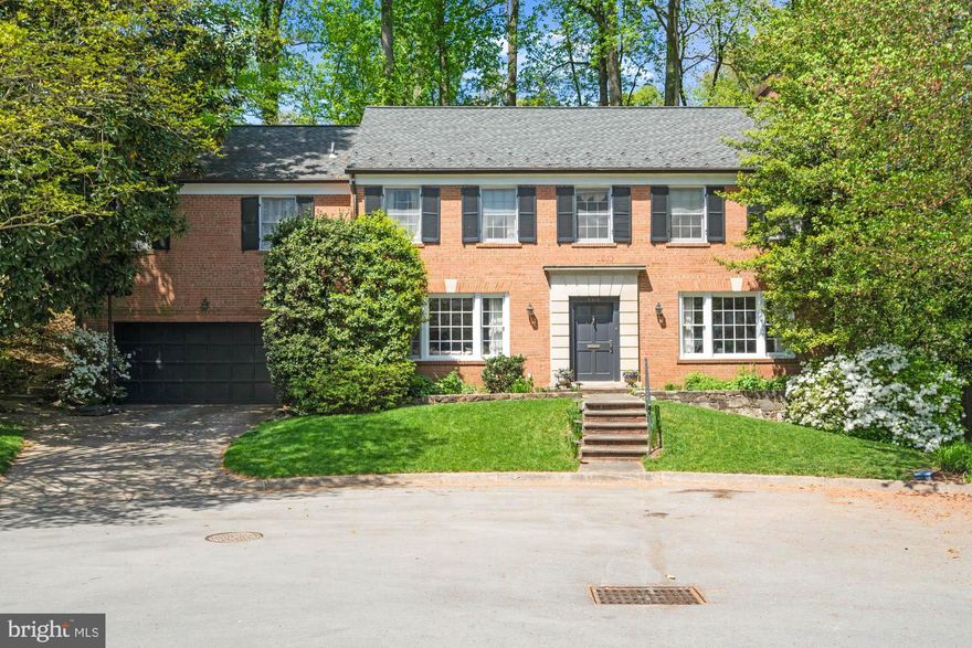 Park-like setting, so close in. Classic elegance in one of the most appealing locations in the National Capital area, this handsome brick colonial is sited in the keystone position of a hidden yet vibrant Bethesda cul-de-sac. Welcome to 5316 Cardinal Court in the coveted Sumner Park area of Westmoreland Hills.

Backing to private parkland and brimming with curb appeal, it charms with a classic brick façade punctuated by two oversized bay windows, gorgeous flowering shrubs, and mature trees. Flagstone patios and walkways smoothly rise and fall among the tiered gardens, creating a very special and private experience.

This quintessential five-bedroom home shines with its hardwood floors, decorative moldings, arched doorways, and gracious room sizes. It’s perfect for large-scale entertaining or intimate gatherings.

With more than 4350+/- SF, the traditional floor plan allows for various types of entertaining. The sizable living room is

anchored by a gas fireplace with decorative mantle; it provides enough room for multiple seating areas and decorative options. The living room leads into the formal dining room which features dentil molding, lighted tray ceiling, and views of the expansive garden. The additional garden room with soaring vaulted ceiling brings a connection to the outdoors for everyday living. The library features floor-to-ceiling built-ins that can accommodate any bibliophile’s collection. It also includes the first of two powder rooms on the main floor for added convenience. The formal powder room serves guests from the front foyer.

The heart of the home is a functional eat-in kitchen that offers table space, ample granite countertops for food prep, a walk-in pantry, an additional buffet area, and access to the oversized two-car garage. Bringing home groceries has never been easier. The accessible stone patio, draped with flowering vines and shrubs, provides space for grilling and serves as a private respite for a cocktail or coffee.

Upstairs, the versatile floor plan features four large bedrooms, a sitting room, a laundry room, and attic storage. Thoughtfully expanded, the primary suite’s private sitting room anchors the resort-like space and features access to a private stone patio and terraced garden, a custom walk-in closet, and an en suite full bath. Three additional bedrooms and two full bathrooms round out the floor plan: One bedroom features a private balcony, which can be finished for daily enjoyment, while another includes an en suite bath. All feature hardwood floors, tall ceilings, and large closets.

The spectacular garden level features a recreation room with a fireplace, a kitchenette, a storage room, another half bath, and an oversized fifth bedroom. This unique garden level allows for easy access to the expansive, wooded, and flowering lot. Additional features of this home include an attached two-car garage with a private driveway.

The dramatic lot offers elements of privacy and grand-scale options. Professionally landscaped and well-cared-for by the fastidious homeowner, this large lot offers enjoyment as it is, with its multi-tiered gathering areas, or for future enhancements such as a play space, garden, or pool. Private and secure access to the protected parkland adjacent to and behind the property provides homeowners with an ideal connection to the trails and parks of Bethesda.

This spectacular residence offers tranquil living while being close to both Spring Valley and Westbard Square shopping districts, the Metro, downtown DC, and Bethesda. Steps to the Capital Crescent Trail, Little Falls Park, and Westmoreland Park. Westbrook, Westland, B-CC schools serve the neighborhood. Inbounds for Little Falls Swimming Club. It also offers the best cul-de-sac gatherings anywhere. Welcome home.
