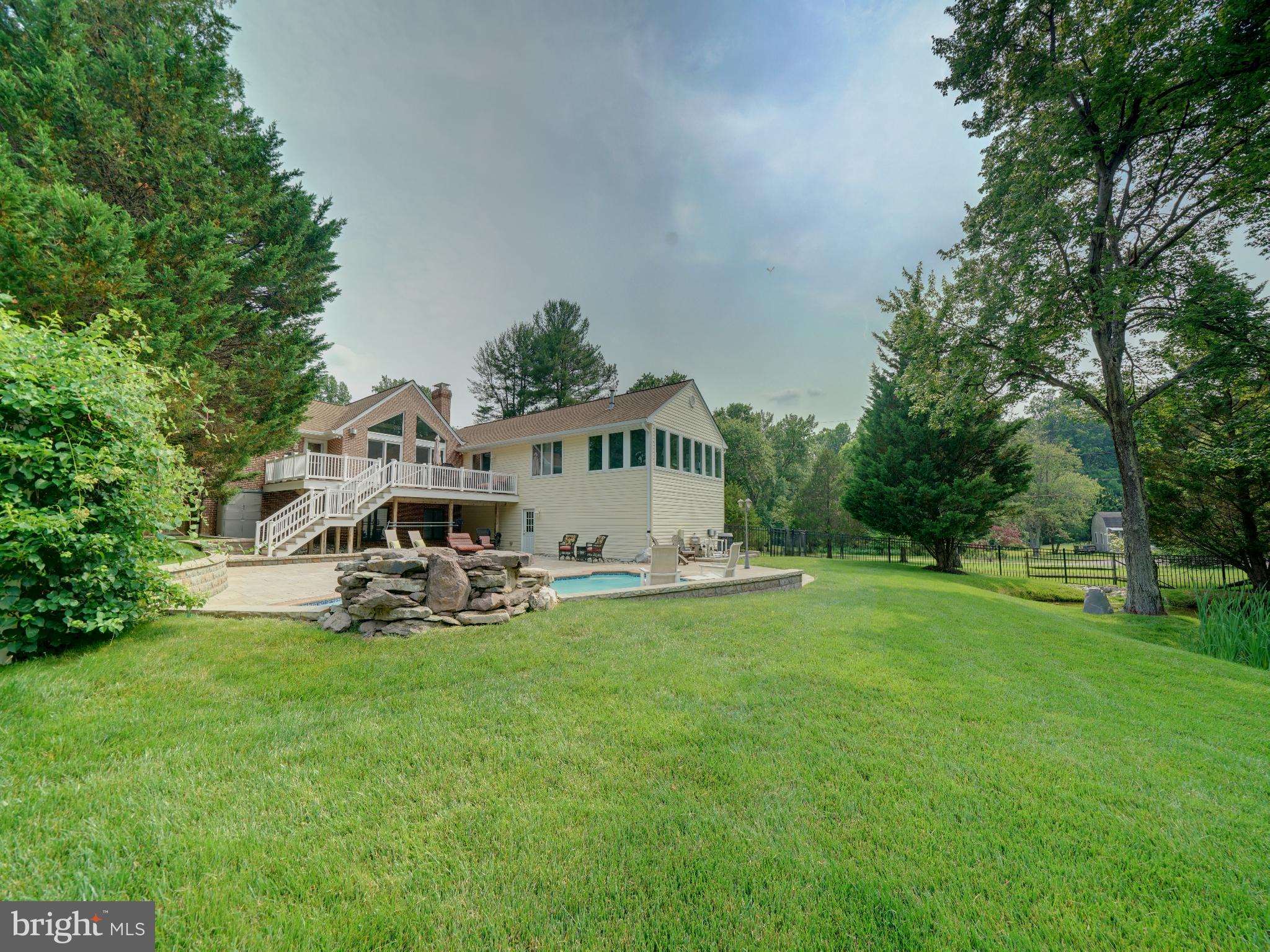 A unique custom built home! Brick front transitional rancher with oversized 4 car garage, natural pond with fountain, inground pool with waterfall, on just over 1 acre. Looking for a room with a view? It is hard to pick just one! Almost every room has a unique view of trees and all rear views are water views of the pool and pond. From the front angle you would not expect to find over 4400 sq ft of living space but it's all here. A traditional look from the outside but a modern contemporary floor plan inside. Entering from the covered front porch, the main level features cathedral 2 story ceilings and 2 oversized sliders with transoms. These combine to make for a bright and airy main living space. Formal dining room open to the sunken great room. Double sided gas fireplace shared between the great room and the kitchen. Both great room sliders access the large tiered Trex deck. The 14x26 ft kitchen has a unique box bay table space with built in seating with vaulted ceiling and a picturesque Palladian window looking out to the Ginga tree. Center island with breakfast bar. Granite countertops. Omega solid wood cabinets with pecan finish, under cabinet lighting. Newer appliances including the built-in convection KitchenAid oven, SS Whirlpool Profile refrigerator and KitchenAid SS dishwasher, all less than 1 year old. Double door pantry with wood shelves. Backdoor off the kitchen leads to deck, perfect for grilling. Center of the home has an atrium with another slider access to the deck. There are 3 bedrooms and 2 full baths on the main level including a 22x30 primary suite. Inside the primary suite you will again find the 2 story cathedral ceilings, double sided gas fireplace, and plenty of natural light from all the windows. A sunroom is included inside the suite and features panoramic views from the 3 walls of windows. The generous walk in closet adjoins the primary bath. Separate vanities, expanded tiled shower and whirlpool/ jetted Kohler tub. The hall bath services the 2 bedrooms, currently used as an office and gym. 1st floor laundry room has built ins and access to huge walk in storage closet. Open staircase to the lower level that is finished with family/rec room and plenty of storage space. Wet bar, refrigerator, pool table/gaming area, huge walk in closet with storage and the 3rd full bath. There are 2 laundry rooms in the home. One on the main level and another in the utility/storage room on the lower level. There are 2 HWHs, and 2 zone HVAC. The 4 car garage is 24x48, (2 9ft doors and 2 10ft doors) with plenty of room for vehicles or great space for storage. There is a 5th bay inside that is now a workshop/storage area. New HVAC 2025. The addition, pool and extensive remodeling was completed in 2004. Patio and hardscape redone 2022. Most paint, carpet and LVP was done in 2021. The entire yard is partially fenced by "neighbors" fencing. Survey just completed with staked corners. The owners black aluminum fencing was installed to enclose the pond and pool areas and it separates the lot around the middle of the property, inside the property lines. Large shed w/elec is beyond the fence. The rear lot goes back to the trees along the back property line. Plenty of room to garden, practice golf shots or play some ball! Pine Valley is a lovely community with a mix of homes of various designs and ages. Most are on acre lots and were custom built. Pineway leads to the Harding Road access to Scotts Cove/Rocky Gorge Park. Short walk to the park and paths along the reservoir or obtain a permit from WSSC and you can launch a watercraft onto the reservoir. Kayak, fish or take a boat out on the water just to observe nature. Birds love it here. Convenient to Maple Lawn, Columbia, JHUAPL, NSA/Ft Meade and BWI. Southern Howard County Laurel/Scaggsville still has so much country feel but yet it is convenient to major routes I95, Rt 32 and 29. This home and the community has so much to enjoy! Call your agent for your own private tour.