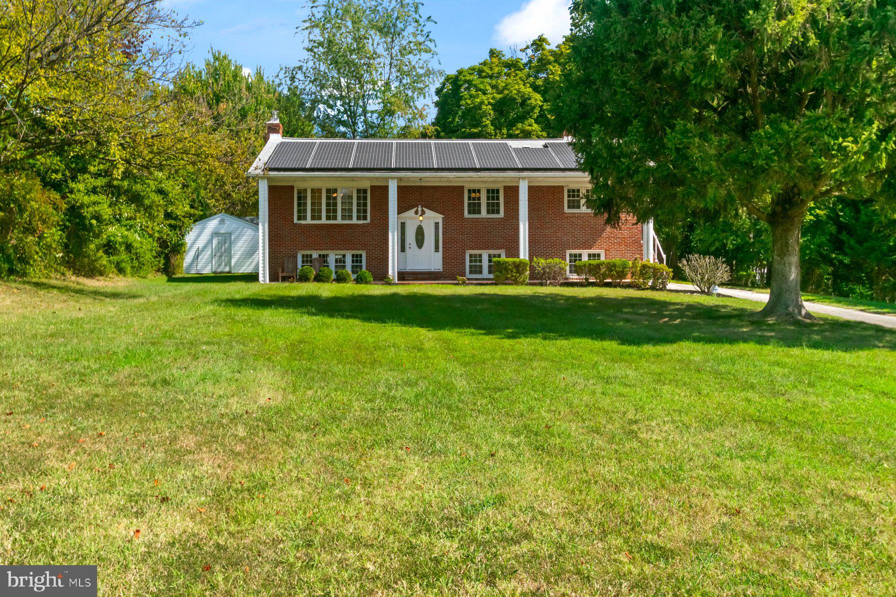Own a little bit of country in convenient Ellicott City! Welcome home to this splendid 5 bedroom, 3 bath split level on 1 acre of tranquil, flat, and tree-lined property. Freshly refinished hardwood floors, new paint throughout and a redone, open floor plan on the main level have transformed this solid brick home into your modern living space. The chef-ready kitchen features a gas range and double oven, updated microwave and dishwasher, an upscale pot rack for additional storage, and a brand new fridge. With only wood and tile throughout, your new home is allergy friendly and easy to clean.
Cozy up in the winter with an efficient firewood insert fireplace, cozy baseboard heat, or in the screened in porch hot tub. Stay cool in the summer courtesy of your new fully paid for, not leased, solar panel array powering AC, or set up a hammock outback to enjoy the breeze on your private, park-like, wooded back yard. The screened porch overlooks a serene, nearly 1 acre yard, complete with a 2-year-new handyman’s dream massive shed and workshop. This property is garden-ready, with a path to the previous owner’s full-sun gardening space. A laundry chute makes cleaning clothes a breeze. The attic features ample storage, and the utility room is expansive with a second, newer fridge. A 5-year-new roof, gutter system with gutter guard, and solid brick construction keeps your family protected from the elements.
Solar panels on this home are paid off in full. Sellers have received enormous energy savings as well as SREC credits. In short: when you live here you save big on energy costs AND you can get paid to do it.
This home is located in desirable Ellicott City school districts and is convenient to amenities, Routes 100/95/29, Columbia downtown, and historic Ellicott City. Featuring ample parking space, get ready to entertain your guests by inviting them to your piece of the country in center of suburban Howard County. Hurry, at this price and with tons of recent updates, this one will go fast!