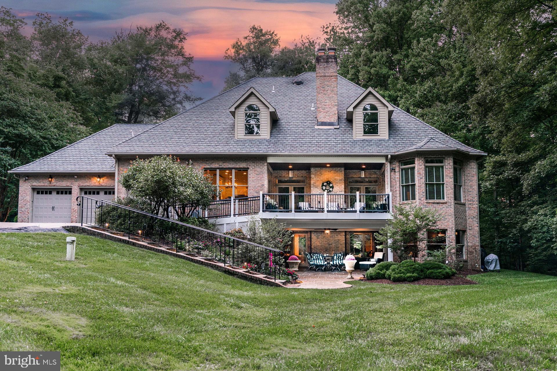 Come experience an estate where incomparable luxury meets pastoral elegance in this custom, all brick French Tudor on one of the largest lots in The Reserve. The Reserve, an exclusive community located in Upper Marlboro, MD, is an enclave of only 40 supreme custom homes on 1+ acre lots. No two homes are the same and many are still owned by their original owners. Sited on one of the most coveted lots in The Reserve, 14409 is being offered for sale by its original owners. You won't find an offering like this for miles, featuring almost 7,000 SF of finished living space with Brazilian cherry floors, a rear entry 3 car garage and 5.5 acres of land. This home is your own private sanctuary and cannot be viewed from the street. You approach the home via a long, private driveway that adds to the feeling of privacy and seclusion. A circular driveway adorned with mature trees and exquisite landscaping welcomes you as well. The back of the property has both flat land for the addition of a pool and rolling hills surrounded by trees on all sides.
Once inside you're greeted by a two story foyer flanked on either side by an office/music room with fireplace and built-ins and an embassy-sized dining room just perfect for large-scale entertaining. The heart of the home is the great room and kitchen which have views of the expansive grounds. The great room features a floor to ceiling wood-burning stone fireplace and direct access to the newly expanded upper level covered porch with a wood-paneled ceiling. Light just pours in from every angle on this floor and offers the warmth and coziness of a more modest home without sacrificing space. The kitchen is a chef's dream with custom cabinetry, granite counters, stainless steel appliances - including a new double oven - double sink, island with a prep sink, and separate pantry. The owner's suite is also on this level and offers a spacious bedroom with a seating area, new luxury bath with two custom marble-topped vanities, porcelain and marble tiled spa shower, free standing soaking tub, separate water closet, and custom closet that you'd normally only see on television or in the movies. Finishing out this level you'll find a laundry and mudroom leading to the rear entry, three car garage. Many garages are normally overlooked, but this one has been outfitted for the automotive connoisseur. Impeccably clean and thoughtfully designed, this oversized garage feels just as luxurious as the rest of the home and is outfitted with epoxy coated floors and custom metal storage cabinets that include a sink.
Upstairs offers a gracious landing with custom built-ins, three bedroom suites all with custom walk-in closets, and two full baths - one en-suite and one buddy bath with separate vanity areas. An additional feature of this level is a custom dressing room which offers additional storage for clothes, shoes, bags, and evening wear.
The walkout lower level is an entertainer's dream! It features a huge recreation room with another floor to ceiling wood-burning stone fireplace, custom bar with a wine/beverage refrigerator, game room, pool table space, theater room, and 2nd kitchen/butler's pantry with full size refrigerator, warming drawer, wine/beverage fridge, plus storage and prep space for all of your entertaining needs. An enormous bedroom /exercise room and full bath round out this level. From this lower level you walk out to a stone covered patio with wood-paneled ceiling and direct access to the remainder of the grounds.
This home has been impeccably maintained and updated and is ready for its next owners to call it home. Some other home highlights to note include: custom brick and stone piers at the entrance of the driveway and flanking the front of the home, custom landscape lighting, interior sprinkler system, exterior irrigation system, interior and exterior surround sound system, a recently added walk-up ramp from the garage pad to the upper level deck, and security system.