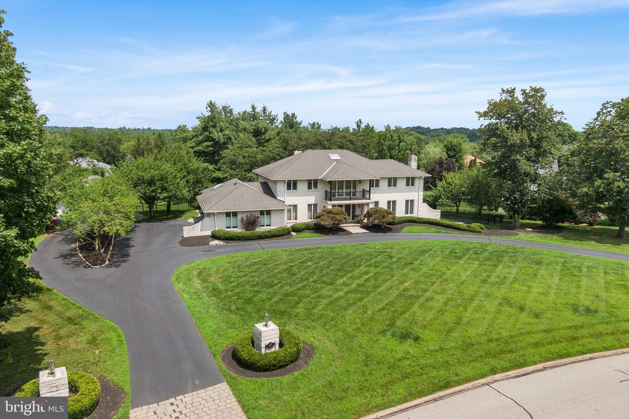 Welcome to this estate-style residence nestled in the heart of Gwynedd Valley, offering timeless elegance, modern comforts, and exceptional space both inside and out. As you approach via the circular driveway, you're greeted by a covered front porch accented with a charming second-story balcony—a grand first impression for this magnificent home. Enter inside to a soaring two-story marble foyer, highlighted by a sweeping curved staircase. The formal living room is bathed in natural light from a wall of windows and features a cozy fireplace. Nearby, a private study with a wet bar and sliding glass doors opens to a covered patio framed by a picturesque brick arch. Entertaining is effortless in the expansive family room, complete with exposed wooden beams, a second fireplace, and large windows overlooking the backyard. This flows seamlessly into the sunroom, perfect for casual dining, which connects to a spacious eat-in kitchen featuring a Sub-Zero refrigerator, 6-burner Jennair cooktop, double wall ovens, vaulted ceilings, skylights, radiant heated and cooled floors, abundant cabinetry and countertops, and a center island for gathering and cooking. The laundry room provides access to the attached two-car garage and a side door to the driveway for added convenience. A formal dining room, ideal for holidays and celebrations, and a powder room complete the main level. Upstairs, a beautiful catwalk hallway leads to the front brick balcony and separates the private primary suite from the secondary bedrooms. The primary suite is a true retreat with tons of windows, access to a rear private balcony, and ample closet space. The ensuite bathroom includes an oversized jacuzzi tub, a makeup vanity with dual seating and a sink, a separate shower room with an additional vanity sink area. Three generously sized secondary bedrooms share a full hall bath, offering comfort and space for family or guests. The finished basement offers flexible living space—currently configured as a billiards room with a full bar, wine storage, and even a stage area—perfect for a second office, playroom, or creative studio. Access outside onto a stone rear patio from sliders off the kitchen, ideal for entertaining. The statement steps lead to a sprawling, private backyard, perfect for outdoor activities. A separate three-car detached garage offers even more parking and storage, complementing the two-car attached garage. Additional highlights include a whole-house generator, extensive exterior lighting, and a location just moments from Gwynedd Valley SEPTA Station, Montgomery County Community College, Gwynedd Mercy University, and an array of shopping and dining options. This is more than a home—it’s a lifestyle. Schedule your private tour today!