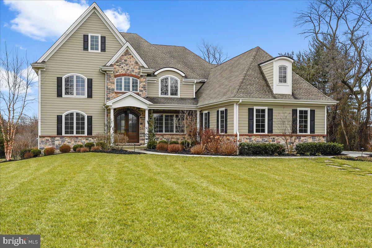 5 Carnation Lane sits at the end of a cul-de-sac of large lots with no HOA. While close to major commuting and shopping routes (202 & 1), you experience only serenity in this idyllic 2 acres of Chadds Ford Township. This Megill Homes Lafayette model home is available only due to a corporate relocation. There are so many desirable features to this gorgeous custom-built home. Built in 2017, the floor plan provides a generous AND cozy home with multi-generation comfort. A covered front porch and custom, arched mahogany french door welcome you inside. In addition to formal living and dining areas, the main floor offers a spacious guest suite with full bath, walk-in closet, and view of the fenced back yard. You’ll want for nothing in the kitchen with gas cooktop and overhead exhaust, double wall ovens, contrasting island, abundant cabinetry and pantry. The family room has a box beam coffered ceiling and remote controlled gas fireplace. From the kitchen dining area, walk out to the Timbertech deck with steps down to the flagstone patio and fire pit and fenced back yard.
From the deck you can access the mudroom and 3-car garage with 50 amp EV Charging port.
The 2nd floor is accessed from a wide, split staircase. The primary bedroom suite features hardwood floors, two walk-in closets with custom closet storage systems, and a luxurious bathroom with heated floors.
There is a large guest room with en suite bathroom, and two large guest rooms share a jack-n-jill bath. Notice the arched casement windows!
The executive’s home office has gorgeous views of the backyard with its southern exposure. There are also custom built-in cabinets and adjustable bookshelves.
The fun continues in the finished walkout lower level. The bar has a kitchen sink, microwave and beverage fridge. There is a gathering/screening area, room for a pool table, a fitness/flex room with 2 windows, huge walk-in closet, a full bathroom, and a 1,000 bottle climate controlled wine cooler. Plenty of storage room in the unfinished areas of the basement where you also find your electrical panel (Generac generator included), 2 tankless hot water heaters, furnace and water softener.
This home is clad in Hardie fiber cement siding and stone with brick trim. Notable architectural features like arched gables and casement windows add to the curb appeal. QBW Builder warranty transfers to new owner. See MLS Attachments for additional details about the property and location.