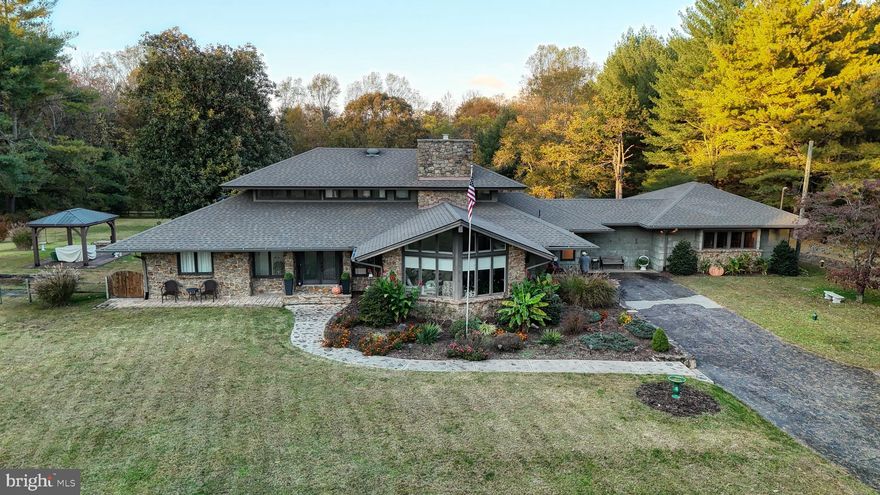 Welcome to this lovely mid-century modern home located on almost 4 acres next to a nature preserve! This will appeal to all the nature lovers and gives a feeling of peace when you visit. Home is across Abbotts Pond, so fishing and canoeing are just a short walk away. This home has a beautiful stone entryway with a sunken living room, while the front living/family area has large floor-to-ceiling windows that allow ample natural daylight to flow through the home, and a large, time period-appropriate stone fireplace for ambiance and a secondary heat source. The kitchen has beautiful stone countertops, upgraded cabinets, stainless steel appliances, with a window for more natural daylight. The guest bathroom and laundry room have been newly renovated with all-new tilework.  The primary bedroom is on the First floor, and the ensuite bathroom has dual sinks and a spacious garden tub for soaking enjoyment. Upstairs, you will find 3 bedrooms and a full bathroom. Outside there is ample space for family events, intimate dinners or barbecues, gardens, a pool, or whatever else suits your needs and wants.