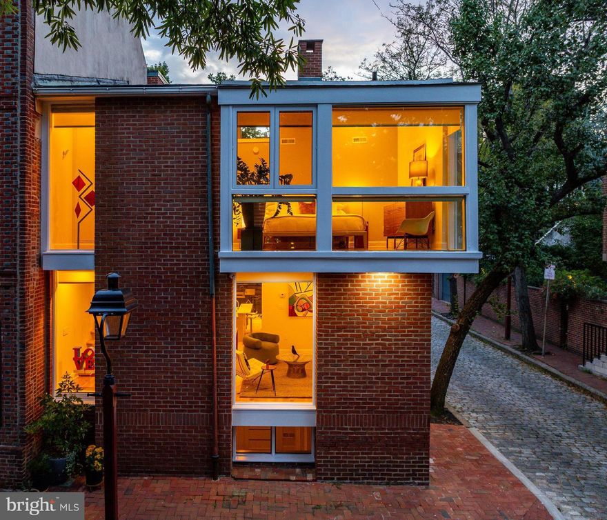 The Nancy Grace House — A Mid-Century Modern Landmark in Society Hill
A rare opportunity to own an architectural landmark in the heart of Society Hill. Poised at the corner of Fourth and Cypress—front door addressed 400 Cypress yet also known as 318 S. 4th Street—this residence was commissioned in 1960 for Nancy Grace and designed by the celebrated Philadelphia firm Stonorov & Haws. With bold Mid-Century Modern lines, sculptural chimneys, and expansive walls of glass, the home embodies the firm’s modernist vision while harmonizing with its colonial surroundings through its brick construction. Recognized for its significance, it was added to the Philadelphia Register of Historic Places in 1999, securing its place as one of the city’s most distinctive residences.
Set on a 23' × 70' corner lot, the home offers a rare brick driveway and courtyard that accommodate two cars while doubling as a private outdoor retreat. Inside, the first floor is designed for openness and flow: a glass-capped partition defines the living room from the dining and kitchen areas, maintaining a sense of light and continuity. The kitchen is highly functional, with granite countertops, custom cabinetry, stainless LG appliances, an oversized picture window that frames the courtyard, and space for four counter stools. Newly refinished white-oak floors run throughout, and a gas fireplace anchors the main living space.
The second floor hosts two bedroom suites. The corner suite faces Fourth Street, wrapped in dramatic window walls and vaulted ceiling detail, with Lutron electronic blinds for convenience. The second suite overlooks the courtyard, offering exceptional privacy and a large walk-in closet. Bathrooms are updated with marble vanities, illuminated mirrors, and glass-enclosed showers.
The finished lower level, complete with a third full bath, provides flexible living space—perfect as a media room, gym, home office, or guest suite. Fresh interior and exterior paint, combined with thoughtful upgrades, preserve the home’s mid-century character while ensuring modern comfort.
Situated among cobblestone lanes and historic brick facades, this home enjoys one of Philadelphia’s most desirable locations. Beyond Washington Square and Old City’s galleries and restaurants, it is also just a stone’s throw from Three Bears Park, ACME, CVS, Whole Foods, and the lively Headhouse Square Farmers’ Market.
400 Cypress Street is more than a residence—it is a piece of Philadelphia’s living history: a modernist landmark commissioned for a remarkable Philadelphian, designed by one of the city’s most influential firms, and lovingly updated for life today.