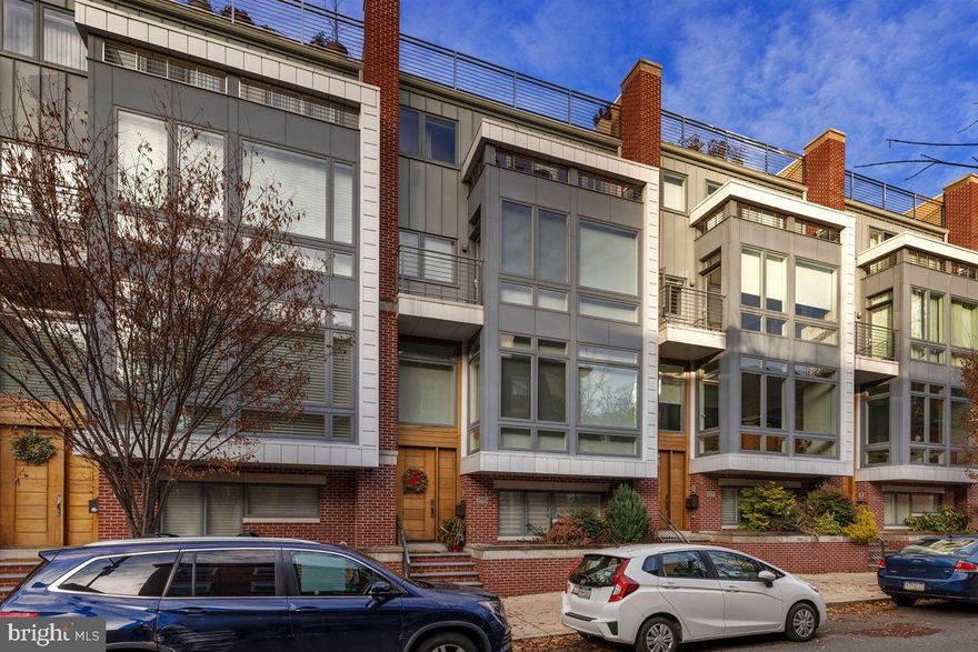 Immaculate, sun-drenched interiors, all accessible via elevator, and outdoor spaces with stunning skyline views are yours to enjoy at this move-in-ready townhouse a stone’s-throw from the Franklin Institute, a 10-minute walk from the blue-ribbon Albert Greenfield Elementary School and only five minutes to Coxe Park and the Schuylkill River Trail. Built in 2015 and still under tax abatement, this residence is on a tree-lined residential block and has a two-car garage. Throughout are upgrades and extras that set this townhouse apart. A main living area with floor-to-ceiling bay window and wood floors is awash in sunlight with a timeless tile accent wall surrounding a gas fireplace. This front-to-back, open-plan space accommodates a dinner-party-sized dining area and a fabulous kitchen with island, all smartly designed and loaded with storage. Chop, cook and clean up with ease with a six-burner gas Wolf range, separate Wolf wall oven, built-in microwave, Sub-Zero refrigerator and prep sink in the island. A dry bar with wine cooler completes the kitchen. Enjoy the large, private deck off the kitchen for al fresco dining and lounging. It has a gas grill hookup and a hose bib. Alternately, take the party to the two roof decks, accessible via elevator and stairs, where the Philadelphia skyline surrounds you with sunrise-to-sunset views. For convenience, a wet bar with wine cooler and a powder room are located between the decks; one deck has a power-operated retractable awning. The primary bedroom suite, on the fifth floor, is an expansive retreat with a private balcony with skyline views, sleeping quarters with space for a sitting area, a walk-in dressing room lined in built-ins and organizers, and spa-like bath with radiant-heated floor. A freestanding steeping tub, oversized shower with bench and multiple sprays, toilet room and wall-length double vanity are finished in neutral tile. A special pressure tank ensures great water pressure to this and the two secondary en suite bedrooms on the fourth floor. The secondary bedrooms each have walk-in closets with organizers. One of the baths features a tub/shower, and one features a stall shower. A fourth en suite bedroom, on the daylight lower level, is perfect for an au pair or in-law as it accessible from the garage and the main entrance. For the buyer seeking a playroom, gaming area, fitness room or home theater-style space, the lower level is finished and provides comfortable bonus space. If you're seeking easy city living with parking, outdoor space and a wonderful, community-oriented Art Museum/Rittenhouse neighborhood, this impeccable townhouse is a must-see.