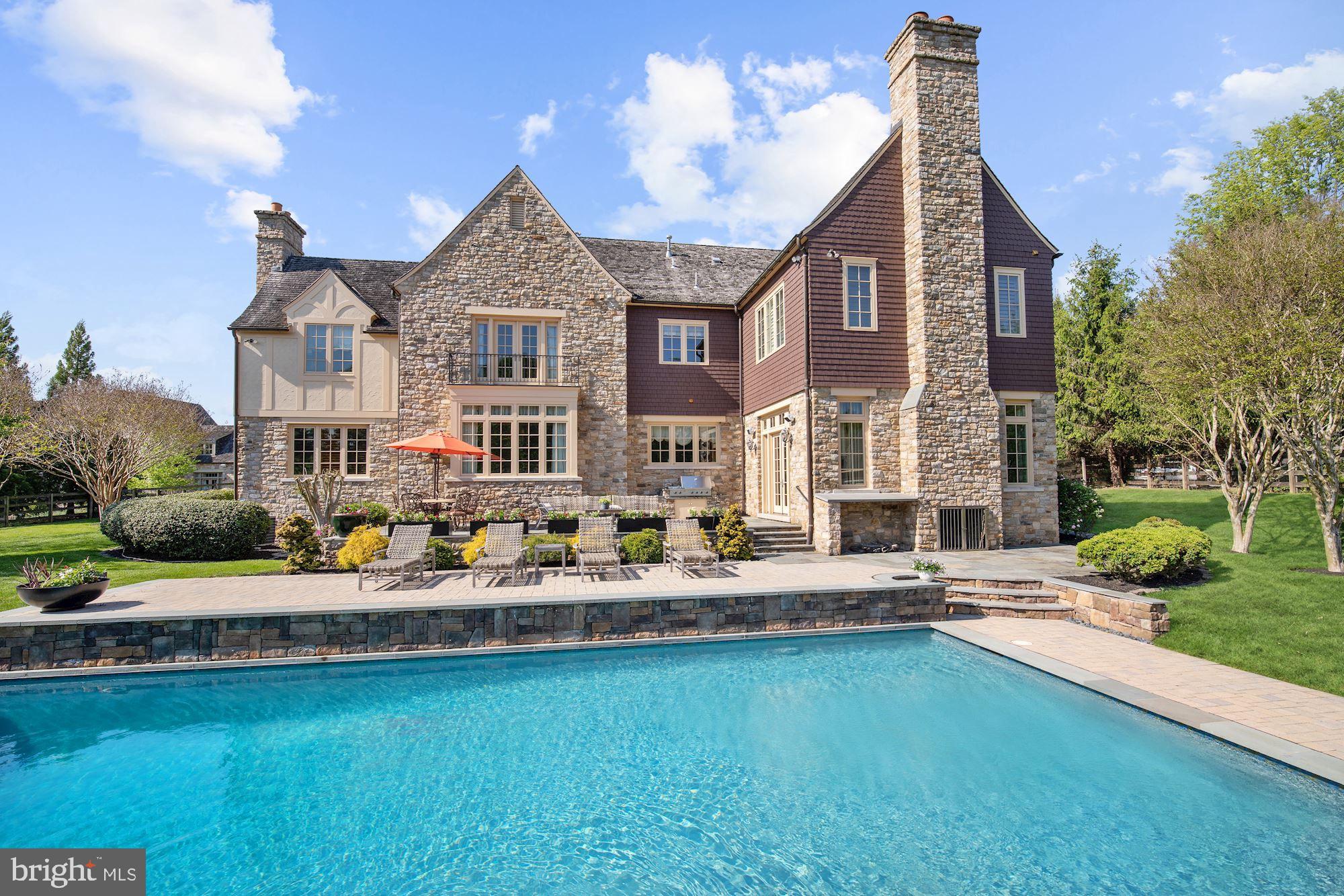 Exquisite English country manor home with wonderful grounds featuring new infinity POOL! Designed by architect David Newman and built by Brendan O'Neill in 2003, the property is located on the incomparable Red Barn Lane, an exclusive enclave of grand stone homes set on lovely 2+ acre lots with stunning views of the rolling Potomac countryside. A cobblestone drive leads to this home's impressive exterior featuring stone and stucco construction, cedar siding, leaded glass windows, a grand entry door and covered breezeway wrapping around to the detached 3-car garage. The delightful interior offers a wonderful flow with large light-filled rooms, random width pine flooring, soaring ceilings, roughhewn ceiling beams, fine panelling and trim work, and multiple fireplaces, on 7,590 square feet of finished space. Every room offers views of the landscaped setting, the new infinity pool and spa, columned and walled boxwood gardens, and sprawling lawn leading to distant trees and stream. The gourmet kitchen at the center of the home offers a large island, six-burner commercial-grade stove, hand painted Italian tiles, and opens to the breakfast room which extends through French doors to an enclosed stone patio and garden. The family room with stone fireplace opens to the terrace spanning the rear of the house. The office or living room has exquisite chestnut-hued panelling, and the lovely large dining room sparkles along with its crystal chandelier. A side entry to the home brings one to a generous garden/mudroom with sink and shelving, sitting area, and full bath for bathers or pets. Upstairs, the owner's suite offers a gorgeous sitting room/office and large private owner's bath. Three additional large bedrooms are served by two generous bathrooms and laundry. The newly finished lower level of the house provides an extra bedroom and full bath, a living area, recreation room, gym and media room. This home provides a luxurious setting for quiet living - with the ability to entertain indoors and out - in the most tasteful and appealing of indoor and outdoor spaces!
