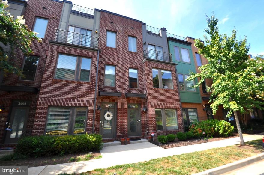 This four-level townhome in Mosaic District combines light, space, and comfort in every room. The main level features hardwood floors, tall ceilings, and large windows that brighten the open living and dining areas. The kitchen includes granite countertops, stainless steel appliances, soft-close cabinets, and under-cabinet lighting. A private deck extends the living space outdoors.
A dedicated home office sits just off the entry. Upstairs, two bedroom suites include full baths and access to a private balcony. Laundry is conveniently located on the same level.
The top floor offers a third bedroom suite with sitting area, full bath, and direct access to a private rooftop terrace with a retractable awning. Throughout the home, you’ll find thoughtful upgrades like custom paint, Hunter Douglas window treatments, blackout bedroom shades and built-in garage storage.
Enjoy Avalon pool and gym access, plus walkable dining, Dunn Loring Metro, and quick access to I-495 and Inova Fairfax.