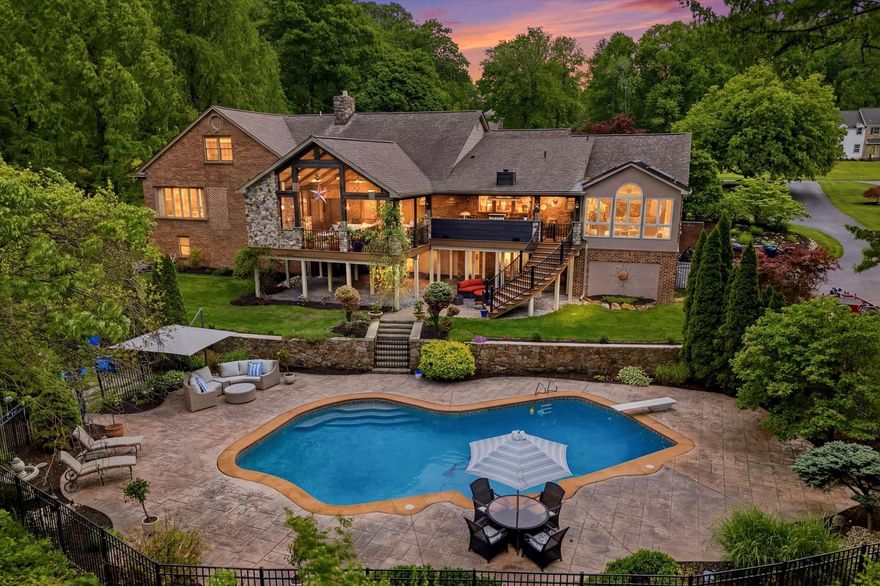 Nestled on two combined lots totaling 2.5 picturesque acres in the award-winning Downingtown Area School District, this extraordinary Bernie Hankin original custom residence offers approximately 5300 square feet above grade square feet!  Beyond, it has approximately 2,200 additional finished square feet in the walk-out lower level!   This home sits at the end of a cul-de-sac so you can be assured it will always be quiet.  The circular driveway, professional landscaping with low-voltage lighting, and a stunning fieldstone and brick façade create unforgettable curb appeal, while breathtaking panoramic views extend for miles from nearly every angle of the home.

Designed for both luxurious everyday living and exceptional entertaining, the outdoor oasis features an 840 sq ft concrete in-ground pool with dimmable lighting, stamped concrete surround, aluminum fencing, secluded fire-pit area, greenhouse, and fenced raised gardens. The spectacular heated covered deck—complete with full outdoor kitchen, propane grill, stone fireplace, heaters, built-in speakers, and included outdoor TV—creates the ultimate year-round gathering space.  This outdoor living space with its curved staircase was one of Keystone Builders showcase designs for many years.  

The travertine paver walkway leads you to a covered porch and a beautiful double door entry.  The dramatic foyer with wood feature wall opens to a sunken living room featuring vaulted beamed ceilings, a striking two-story stone wood-burning fireplace, and an upper loft reading nook with built-in bookshelves. Crown molding, updated baseboards, hardwood and LVP flooring, stylish designer accent walls, and abundant natural light elevate every space.  The beautifully renovated kitchen opens seamlessly to the sitting room and showcases a massive 9.5-foot double island with quartz counters, induction range with hood, wine refrigerator, stainless steel appliances, built-in microwave, and custom finishes throughout. There is also a gorgeous sunroom with 6 skylights with miles of scenic views, as well as access to the outdoor living area. 

The main level includes two luxurious ensuite bedrooms, including an impressive primary suite with five closets—two being walk-ins and one as a dedicated shoe closet—and separate his-and-her bathrooms! The first spa-inspired bath includes a clawfoot tub, marble flooring, and custom marble tile work.  The second bath features a walk-in rainfall shower.  Additional main-level highlights include a private office with teak floors and custom built-ins, an oversized dining room with recessed lighting and crown molding, and a spacious mudroom/laundry room with walk-in pantry.

The fully finished walk-out basement is truly one-of-a-kind, offering multiple entertaining spaces including a theater area with 110-inch projection screen and subwoofers, social lounge, wine closet, propane stone fireplace, and an incredible two-tier wet bar with built-in cabinetry, wine fridge, ice machine, and kegerator. A premium $70,000 sound system with five Sonos zones provides immersive audio throughout. The lower level also includes a second seating area and a fully equipped mirrored gym with included fitness equipment.

Additional upgrades include multiple bathroom renovations, roof replacement (2015), newer Pella wood and vinyl clad windows, four heat pumps, three electrical panels, custom travertine front walkway (2021), fresh interior paint (2025), and recently renovated shared upper-level bath serving two spacious bedrooms with walk-in closets. This remarkable property seamlessly blends timeless craftsmanship, modern luxury, and resort-style amenities in one exceptional Exton setting.
