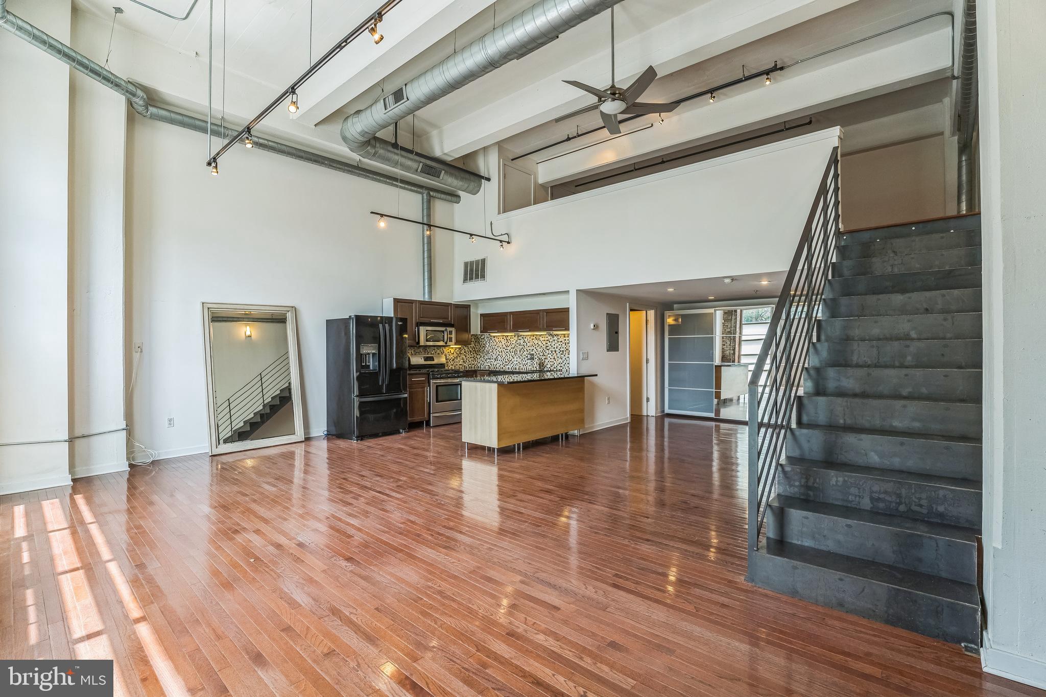 Discover this sleek bi-level loft with deeded garage parking and two private entrances—one opening onto the street directly next to Philadelphia's famous Rail Park and trail. This sun-filled condo features soaring 18'+ ceilings, oversized industrial windows with electric shades, and a stylish granite kitchen with a breakfast bar. Upstairs, the spacious loft bedroom offers a peaceful retreat, while the main level includes a full bath, laundry area, and generous storage with custom closets. Originally built in 1900 and fully renovated in 2007, the home blends historic charm with modern updates. Enjoy a 96 Walk Score and 100 Transit Score, with easy access to Cafe Lift, Underground Arts, Prohibition Taproom, and more. The building also offers a secure mailroom and unbeatable proximity to major highways, public transit, and Philly landmarks.