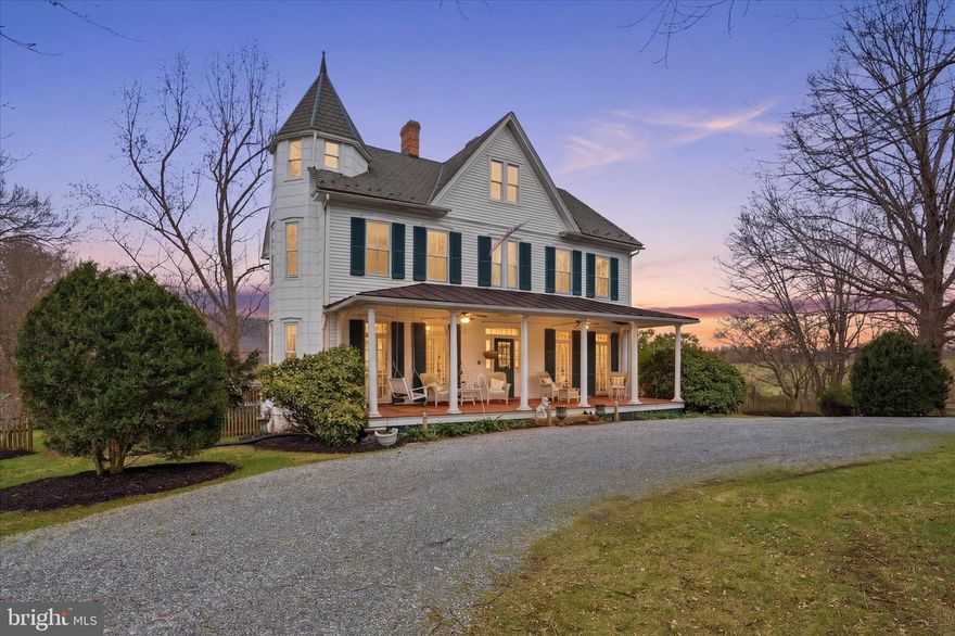 Step into a rare blend of history, character, and countryside charm with this remarkable Queen Anne Victorian estate set on 5.84 scenic acres in Frederick County. Dating back to the 1870s, this center hall-style home offers timeless architectural detail paired with thoughtful updates for today’s lifestyle.
Inside, the 4-bedroom, 2.5-bath residence showcases original moldings, three fireplaces, and beautifully preserved period features. A welcoming covered front porch leads into an elegant interior where former double parlors now create a spacious living room with custom built-ins and coffered ceilings. This home carries endless stories from the Prohibition era, when it reportedly operated as a speakeasy. A government raid during that time left seven bullet holes in the front door—still visible today—offering a rare and tangible connection to the past.
One of the home’s most inviting spaces, the former parlor, has been transformed into an ideal sitting room or lounge—perfect as a cozy retreat, entertaining space, or even the ultimate “man cave,” blending historic charm with modern comfort. The formal dining room is ideal for entertaining, highlighted by a vintage mantel and classic French doors.
The kitchen and adjoining family room strike a perfect balance of old and new, featuring glass-front cabinetry, exposed beams, and a distinctive fireplace with a hearth crafted from reclaimed antique brick. Upstairs, four bedrooms are accessed by a secondary staircase, along with a charming full bath complete with a clawfoot tub and original fixtures. The fully floored attic offers excellent storage or future expansion potential.
Beyond the home, the property is equally impressive. Equestrian and hobby farm enthusiasts will appreciate the three-stall stable, multiple paddocks, fenced pasture, chicken coop, kennel, and gazebo. A detached three-car garage with upper-level space provides endless possibilities for a studio, office, or guest retreat.
The peaceful setting includes a meandering creek, natural spring, and sweeping views of South Mountain. Ideally located near Brunswick, with easy access to Harpers Ferry, the C&O Canal, Appalachian Trail, and MARC train to Washington, D.C., this property offers both tranquility and convenience.
Rich in character and full of opportunity, this one-of-a-kind estate is ready for its next chapter.