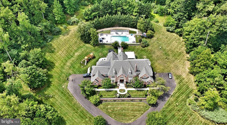 Be prepared to experience the most magnificent home and property currently offered for sale anywhere in the region. Perched majestically with its all brick exterior on a 12.93 acre end of cul-de-sac parcel, 5 Knowles Creek offers the sophisticated buyer the ultimate combination of size, scale, luxury, privacy and opportunity! Located in one of most coveted neighborhoods in Upper Makefield ( w/No HOA ), the owners have meticulously re-engineered, re-imagined, and rebuilt the home and its infrastructure since their purchase in 2018. The statistics are impressive and the superlatives are many – 12.93 Acres; 16,000 sq. ft of finished living space on 4 floors; 6 Garages, 6 Bedrooms, 5 Full & 2 Half Baths; “Almost” Olympic Sized Length Pool. The double door Foyer entry reveals a sweeping staircase to the bridge overlook and upper hall. To the left is the formal Dining Room, to the right the formal Living Room w/fireplace. Immediately evident is the spectacular millwork, gleaming tile, and hardwood floors. The two-story Family Room features an incredible box beam ceiling, fireplace, with side ante room for more intimate seating and entertainment. A cherry paneled Office is tucked away for quiet work or study, and has its own private outdoor patio. The heart of the main floor is the remarkable Kitchen. Replete with multiple counters, sinks, refrigerators, freezers and high-end appliances, space to spread out is not on issue.  A mini-family room and breakfast area adjoin the main area, each with walls of windows. A walk- in Pantry, Butlers Pantry, Mud Room, Laundry Room, two Half Baths, and second staircase complete the splendid main floor. The upper level has a spacious hall and overlook to the foyer and family room. Unquestionably, the Primary Suite, closet and bath are the most stunning, yet tranquil you will find. The Main Bedroom has an entry hall w/ coffee bar, hideaway ceiling TV, see through glass fireplace and Sitting Room overlooking the pool. The closet is larger than most one-bedroom apartments, with built-ins, seating areas, massive storage, and adjoining wrapping/craft room and second laundry room. The stylish, customized millwork is of the highest quality. The Bath is resort like, with enchanting walk-in shower and multiple sprayers, soaking tub, double vanities, and private toilet closet. Three bright and airy spacious Bedrooms (one with a second floor loft) with well appointed baths complete the second floor. The third floor features one amazing Bedroom/Suite, with large entry hall, two sitting areas, huge bath and huge walk-in closet. The lower level will be the envy of any designer, with natural stone abounding, walnut bar, glorious Wine Room, multi-sport simulator, entertainment area with spacious wall for as large a TV as you can find. The game area and beautiful dollhouse are a kids dream! Bedroom 6 w/attached full bath and two large storage areas complete the lower level. Outside, the resort like rear features a full Kitchen with adjustable covering, firepit seating area, play area, and the most magnificent pool with Jericho Mountain as the backdrop. WOW! As if this isn’t enough, the home also boasts smart technology with home automation designed by Brandon Hoishik,  for many aspects of the property. Additional features are Crestron Lights/Switches/Outlets, Floor Logic Water Protection System; Whole House Generator, Central Vacuum, 800 amp Electric Service, Rubberized membrane on entire Foundation; Stormwater Management and more. Ideally located in the heart of Upper Makefield and the Council Rock School District, minutes to 1-95, Trenton Mercer Airport, and to the wonderful towns of New Hope, Lambertville, and Newtown. 60 Minutes to Philadelphia, 90 Minutes to NYC. To replicate this home and property as new construction, a budget of $12-$15 million and 24 months of time will be needed. Why bother? Just move right in to this immaculate, mint condition home, unpack your bags and enjoy life to the fullest!
