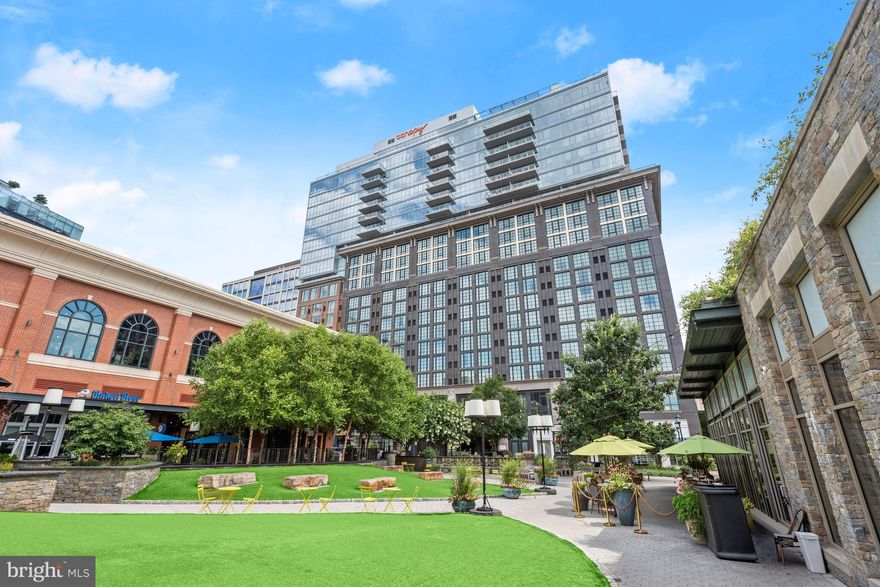 Incredible 19th floor condo in the heart of iconic Pike & Rose in North Bethesda! Just below the Penthouse level, this luxury unit showcases floor to ceiling glass walls with stunning unobstructed views from DC, Dulles, Sugarloaf, and Bull Run mountains. Take in the gorgeous panoramic views with the perfect mix of greenery and city life as well as the breathtaking vivid sunsets from the comfort and privacy of your glass balcony. The well-designed floor plan of this 2 bedroom and 2 bath unit begins with a long hallway from the entrance ensuring separation from other units and any hallway noise. The awe-inspiring interior highlights stylish hardwood flooring, 10 foot ceilings, modern lighting fixtures, and sleek finishes throughout. Prepare decadent dinners in the kitchen appointed with quartz counters, soft close gray cabinetry, oversized subway tile backsplash, stainless steel appliances including a gas range, and a large island with seating. The open concept kitchen, dining, and living areas are ideal for entertaining and everyday comfort. The living room highlights a deep tray ceiling, feature wall, and electric fireplace adding warm ambiance. The wall-mounted TV in the living room is also included. The primary bedroom suite evokes the feeling of a luxury hotel with its own planked feature wall and glass wall. The primary bedroom also hosts a walk-in closet and an en-suite bath with a double vanity, lighted mirror, and large floor to ceiling tiled shower with frameless door. The second bedroom comes equipped with a built-in murphy bed allowing for flexibility between work and living space along with the nearby second full bath.  Optimal storage space abounds with two hall closets as well as a sizable entry coat closet. The unit also offers full sized stacked washer and dryer in a dedicated closet. Additionally, there are added water sensors near the washer/dryer and water closet as a precaution, to provide peace of mind. Custom roller shades are included with the continuous floor to ceiling windows throughout the unit. This unit offers an assigned parking space, near the resident elevator in the underground garage as well as a spacious storage unit.  Well known for exceptional service as well as a comfortable and convenient environment, additional features afforded residents of Pike & Rose are a beautiful lobby and concierge service to welcome you and your guests, bike racks available to all tenants, a rooftop with indoor and outdoor amenities including a lounge with wet bar, dog park, sitting areas with TVs and billiards, outdoor grilling area, and a state-of-the-art fitness center accessible 24 hours a day. Residents are also offered a 15% discount by nearby merchants. Quick and easy access to everyday needs including the White Flint Metro, Trader Joes, Giant, and more. Enjoy the vibrant Pike & Rose premiere outdoor retail center with trendy shops, restaurants, bowling, a cinema, upscale dog park, and farmer’s market.