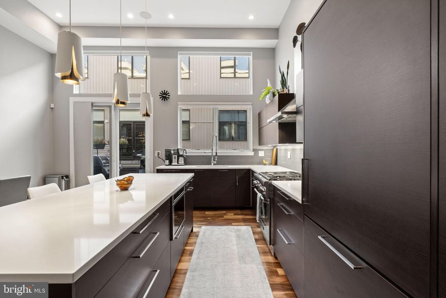 819 N Orkney Street is a striking residence within SEVENTEEN, an exclusive gated townhome enclave in the heart of Northern Liberties featuring 2-CAR GARAGE. Defined by bold graphite brick and aluminum composite façades, this boutique collection sets a sophisticated architectural tone with exceptional curb appeal and modern presence. Offering approximately 3,200 square feet of impeccably designed living space across five thoughtfully planned levels, this home seamlessly blends industrial-inspired elegance with contemporary luxury. Arrival begins through custom iron gates into a private motor court, leading directly to an oversized two-car garage, immediately establishing a sense of privacy and refinement. Inside, the residence features three spacious bedrooms and three-and-a-half luxurious bathrooms, finished with Carrara marble, Porcelanosa tile, and premium Grohe and Toto fixtures. The primary suite is a true retreat, showcasing extensive handcrafted custom storage, concealed media cabinetry, a generous walk-in closet, and an elegant dressing area with additional storage—designed with both beauty and function in mind. A fully finished lower level serves as a comfortable, year-round media lounge, complemented by an adjacent flexible space ideal for a home gym, private office, game room, or optional fourth bedroom. Throughout the home, soaring ceilings ranging from 9 to 14 feet, rich Brazilian Tigerwood floors, Pella Architect Series windows, and custom steel stair railings create a dramatic yet inviting atmosphere.
The chef’s Poggenpohl kitchen is both refined and highly functional, featuring Thermador Professional appliances, quartz countertops, soft-close cabinetry, additional upper storage, and a built-in pantry—perfect for everyday living and entertaining alike. Just beyond, a full-width Trex balcony offers an ideal setting for grilling, morning coffee, or urban gardening. Thoughtful technology is integrated throughout, including Sonos built-in audio, Nest smart thermostats, Schlage smart locks, CAT-5 wiring in all living spaces, recessed lighting throughout, and a dedicated media and security closet. Dual high-efficiency Lennox HVAC systems ensure year-round comfort, while an Air-phone video intercom adds an additional layer of security.  At the top level, a private pilot house opens to a green roof and Trex roof deck, offering sweeping city views, stunning sunsets, and an exceptional space for entertaining or quiet relaxation. Ideally located just steps from neighborhood favorites, parks, dining, and everyday conveniences. Enjoy easy access to neighborhood favorites such as One Shot Café, Café La Maude, Honey’s Sit ’n Eat, and North Third, with countless additional dining and coffee spots nearby. This residence offers the rare opportunity to own a luxury home in one of Philadelphia’s most desirable and dynamic communities. Convenient access tto major highways and bridges, including I-76 and I-95, for an effortless commute.