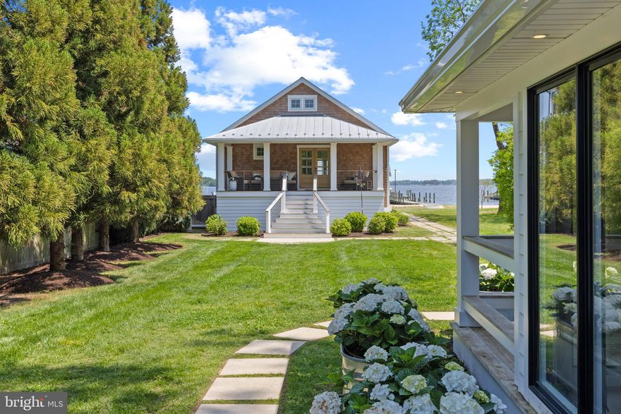 A stunning waterfront retreat offering panoramic views of the Magothy River and your very own private sandy beach. Steps from the water and an easy stroll to the neighborhood waterfront restaurant and marina. Thoughtfully rebuilt inside and out in 2017/2018, this coastal gem blends modern luxury with effortless charm. The elevated main level showcases open-concept living with vaulted ceilings, expansive windows that frame the captivating view and a sleek fireplace wall. The chef’s kitchen impresses with a massive quartz island, top-tier stainless appliances, and a clean design accented by coastal tile. The open floor plan offers easy entertaining with the kitchen effortlessly flowing to the waterside deck for alfresco dining. The outdoor experience rivals the interior—two IPE hardwood decks with vaulted ceilings and ship-lap detail invite you to unwind in style, while a rear deck captures tranquil garden sunsets. The lower level features over 1200 sqft of unfinished storage with an additional covered IPE deck; perfect for soaking in the hot tub and the spectacular views. Inside, the primary  suite is a true escape, complete with a spa bath and sliding barn doors.  The additional bedroom with conveniently located hall bath and the guest cottage with bedroom and bath provides added accommodations for family and guests. For extra charm, there's even a cozy sleeping loft in both the Living room and guest cottage. From the custom storm-rated Anderson sliders to the maintenance-free cedar-look shake exterior and hidden storage beneath, every detail has been meticulously considered. Bermuda shutters offer both flair and function, and the professionally landscaped grounds add to the relaxed, resort-like setting. A detached two-car garage, custom design touches and seamless transitions between outdoor spaces round out this extraordinary property. Whether for weekend getaways or everyday living, this is coastal Maryland living at its most refined. Welcome Home!