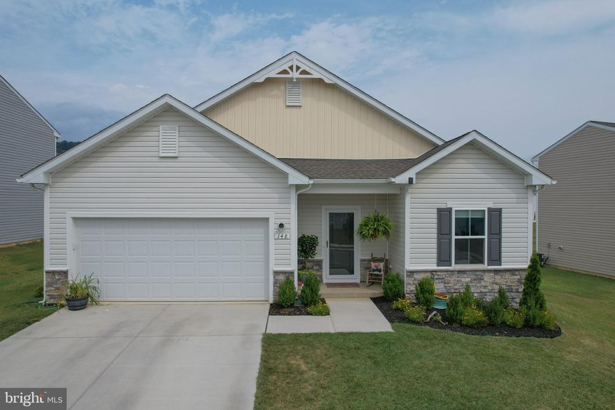 Better than new construction, this 3BR/ 2BA one-level rancher built in 2022  is an absolutely perfect house!  From the well appointed open floor plan to the fenced and curated backyard oasis, you will be saying "YES!" to the house! If you have been seeking a first home or a final home, this could definitely be the one!  Nearly new, this two year old home boast laminate and carpet throughout in a cozy setting nestled in the mountains of Hedgesville, West Virginia.   The kitchen island with bar seating is open to both a large dining area and the living room.  Spacious enough for a dining room table and well lit from the sliding glass door, the dining area provides many options for entertaining. Step out from the sliding glass door and find your serenity under the shade of the newly installed pergola which conveys with the house.  This added bonus will become your favorite spot as your curl up with a great book on the large back patio in the shade of the pergola. The covered patio will become your escape to watch lightening bugs in summer evenings and warm up with coffee on crisp fall mornings. 
The floorplan of this home is incredibly desirable-- especially the seperation of the primary suite and two additional bedrooms.  The privacy of the primary ensuite is emphasized with expansive living/ kitchen space separating the other two (bed)rooms.  The floorplan allows for cozy togetherness and a private retreat for respite.  The two bedrooms on the other side of the house are well suited for many uses.   Guest suite, home office, play room or simply bedrooms, you will use these rooms to suit your living needs.   You will find the closets to be ample and each room very well lit. Centered for best use, the full bathroom shared on this wing provides convenience!  The main living room shall not be overlooked with it's high ceilings and easy comfort.   Watch the game, read a book or simply  relax in what will become your favorite room in the house! If relaxing is not your style,  the two car garage will give you ample space to work on your next project!  The spacious garage has been outfitted with 4 large hanging storage shelves which nearly double the storage capacity!  These convenient and sturdy units also convey with the house.  You will swoon at the level of care this house has!  This location is incredibly convenient to all amenities and has access to I-81 within minutes.  Enjoy the mountain view; welcome to wild and wonderful! Come see for yourself!  Book your tour today!