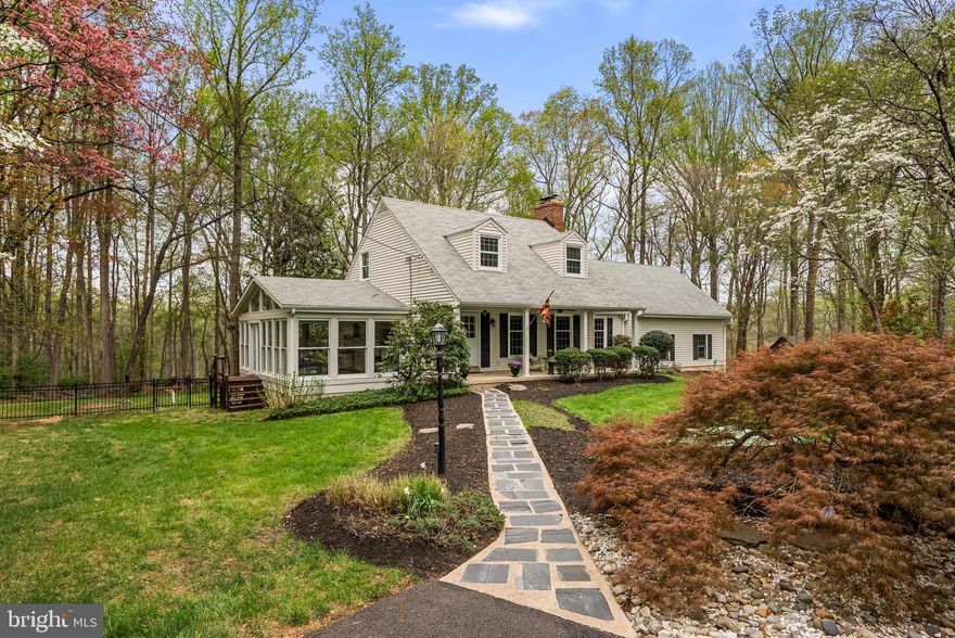 Tucked down a circular drive on nearly two private, wooded acres in Ashton's Bradfords Rest, this one-of-a-kind Cape Cod is the rare turnkey home where a major 2020 renovation meets true, hard-to-find character. Follow the slate path to a deep covered front porch — the kind with custom-painted ceiling detail, outdoor lighting, and a ceiling fan — where mornings start slow and the only traffic is birdsong from the surrounding trees.

Step inside and the home announces itself immediately: refinished hardwood floors, exposed wood beams, crown moldings, and custom built-ins run through the main level. The renovated gourmet kitchen is the heart of the home, outfitted with custom cabinetry, quartz countertops, stainless appliances, and a generous island seating four or more. It opens directly to the dining area in a true open-concept flow, then spills into a showstopping vaulted sunroom wrapped on three sides with windows and served by its own dedicated heating and cooling system — a space that works as hard in February as it does in June.

The living room anchors the main level with a wood stove insert fireplace powerful enough to heat the entire house in winter, while a cozy den off the main hall offers its own wood-burning fireplace, built-ins, and desk nook — ideal as a reading room, library, or home office. Rounding out the main floor: a full bath with a gorgeous tiled walk-in shower, and an expanded laundry room tucked behind custom barn doors.

Upstairs, the primary suite is a true retreat, featuring a walk-in closet, exposed beams, freshly installed luxury vinyl plank flooring, and a new spa-caliber primary bath with a dual vanity, a tiled shower with rain head and body jets, and a separate water closet. Two additional bedrooms share a tastefully updated hall bath.

The fully finished walk-up lower level adds over 500 square feet of flexible living space — perfect as a rec room, media room, or fitness area — plus a dedicated office and a third full bath. Direct walkout stairs to the backyard make the whole level effortlessly usable.

Outside is where this property truly distinguishes itself. A circular drive wraps a central fire-pit gathering area; an extensive hardscape patio opens onto a wooded paradise of mature trees; and a private one-mile nature trail begins just beyond the rear property line, connecting directly to the Patuxent River. The grounds back to parkland and offer the kind of quiet privacy Ashton is known for.

Systems are all handled: two new dual-zone heat pumps with air handlers, newer well pump, replaced acid neutralizer, thermal vinyl siding, thermal replacement windows, architectural shingle roof, 200+ amp electrical service, and fiber-optic internet. A 2-car side-entry garage plus a 4-space driveway means parking is never a question.

Location wise, you're three minutes from GrillMarx Steakhouse in Ashton, and a short drive to Olney's dining corridor — Salt & Vine, Cava Mezze, Olney Ale House, and Fallen Oak Distilling — plus year-round programming at Olney Theatre Center and the trails at Rachel Carson Conservation Park. Commuter lots sit within five miles with a bus stop under a mile, connecting easily to the ICC, I-95, and the New Hampshire Avenue corridor. Assigned to the Sherwood school cluster within Montgomery County Public Schools.

A true private retreat, renovated for today, built to last, and impossible to replicate at this price.
