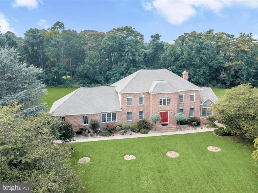 Nestled amidst three acres of lush greenery, this extraordinary all-brick custom home in the sought-after Westside community offers an unparalleled blend of convenience and elegance from the original owners. As you approach the property, a majestic tree-lined entryway welcomes you to this meticulously maintained residence, featuring five spacious bedrooms, three full baths, and two half baths. Step inside the grand two-story foyer, adorned with gleaming marble floors, a graceful, curved staircase, and exquisite lighting. The formal living and dining rooms, perfect for entertaining, exude sophistication and charm. The heart of the home is the inviting family room, complete with a wood-burning brick fireplace, ceiling fan, crown molding, hardwood floors, and access to the patio. The adjacent kitchen boasts a newly installed dishwasher, center island, breakfast bar, stainless steel appliances, recessed lighting, a walk-in pantry, and a casual dining area. Enjoy your morning coffee in the expansive sunroom with its vaulted ceiling or step out to the front courtyard or rear patio for a breath of fresh air. For those who work from home, a dedicated library/home office provides a tranquil and productive space. The main level is completed by a convenient laundry room and two powder rooms. Ascend to the upper level to find the lovely primary suite, featuring a ceiling fan, crown molding, a spacious walk-in closet, and an additional closet. The primary bath offers separate vanities, an oversized shower, and a relaxing Jacuzzi soaking tub. Four additional generously sized bedrooms, including one with an en-suite bath, and another full bath ensure ample space for family and guests. The impressive lower level expands your living space with a bonus room or optional sixth bedroom, a large recreation room with a custom wet bar and fridge, and a spacious utility room with walkout stair access. Central Vac throughout the home. Outside, experience the tranquility of mature trees and landscaped grounds in this ultimate private setting. Updates: dishwasher and heat pump. This extraordinary home is an absolute must-see!