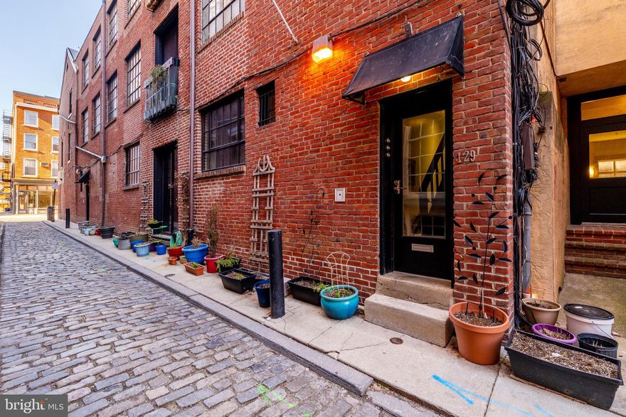 Imagine living on one of the most picturesque & quiet cobblestone streets in a historic Old City boutique building in the showcase unit! No steps to enter this secure, first floor space. This bohemian, 2 bedroom condo is the perfect blend of airy spaciousness, practicality, and character. Special features include a barn door that can be opened + factory loft windows + exposed brick + beautiful stained glass + bedroom doors reclaimed from a school in Western Pennsylvania. The 10.5' ceilings accentuate the open expansive feel when you enter. Note the newly renovated Julia Child "hippie kitchen" with farm sink, high-end Bertazzoni stove, and room for a table and chairs. An office is positioned for people watching when the barn doors are open as part of the loft-style living room (plenty of space). Both bedrooms have doors for privacy and generous closet space. The deco tiled bathroom has style with pedestal sink and tub/shower. Hardwood floors throughout and gas fireplace. Washer/dryer in the unit. Basement storage included. Low condo fees and economical utilities make this a smart buy to live in, use as a pied a terre or for investment. A walker's paradise, 129 Cuthbert St is steps from destination restaurants, theater, art galleries, historic sites, shopping + highways/transportation (SEPTA + PATCO, I-676, I-95, bridges). Easy commute to New Jersey. Value add note: The planned Park at Penn's Landing will include the extension of the South Street Pedestrian Bridge, reconstruction and expansion of a bridge over 1-95 and a portion of the Delaware Trail. Anticipated opening of this $225 million project is 2026. This new park will completely change how residents and visitors experience the waterfront. Schedule your tour of 129 Cuthbert St today! Official public record address is 51 N 2nd St, Apt E, Philadelphia, PA 19106