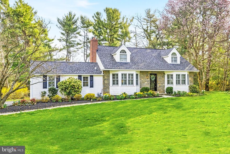 Welcome to 371 Margo Lane—where storybook charm meets everyday practicality in the heart of Berwyn’s beloved Woodlea neighborhood. Perfectly perched on a flat lot, this stone Colonial Cape Cod is the kind of home that makes you slow down and smile (and maybe wave to a neighbor or two).  Built in 1955 and thoughtfully cared for and maintained, this home strikes a delightful balance between classic character and modern comfort. The living room sets the tone with its gas log set fireplace framed by original painted tile—equal parts cozy and conversation starter. Plantation shutters, gleaming hardwood floors, and natural light complete the scene.  The updated kitchen is ready for its close-up, featuring marble countertops, under-cabinet lighting, high-end appliances, and an island perfect for morning coffee or evening entertaining. It flows seamlessly into the dining area, where a wall of windows frames views of the private rear yard and stone patio—ideal for al fresco dinners or quiet weekend lounging.  Just beyond, a sunken family room brings a touch of drama (the good kind) with its vaulted ceiling, heated floors, recessed lighting, and built-in bench seating with storage. A sliding door connects you back outside, while a nearby mudroom with brick flooring and ample storage keeps life beautifully organized. (There’s even a second staircase to the lower level—because one is simply not enough).  The main level also offers a flexible office or bedroom space, a guest bedroom, and a stylishly updated full bath with sleek tilework and a seamless glass shower. Upstairs, three additional bedrooms await, including a spacious primary bedroom with windows on three sides and two closets. The hall bath features a double vanity, porcelain tub, and plenty of cabinetry. The additional bedrooms bring charming Cape Cod character with cozy angles and inviting proportions. Downstairs, the unfinished lower level is brimming with potential—complete with a vintage bar, sitting nook, laundry area, workshop, and utility space. Whether you dream of a finished retreat, hobby haven, or simply exceptional storage, this space delivers. For added peace of mind, the home is equipped with a whole-house Generac generator connected to the natural gas line—keeping life running smoothly no matter what the forecast has in store. And the lifestyle? Walkable to the T/E middle and Conestoga high schools, downtown Berwyn’s shops, restaurants, train, and farmers market, with low taxes and a truly special neighborhood feel.  371 Margo Lane isn’t just a house—it’s a home with personality, warmth, and room to grow.