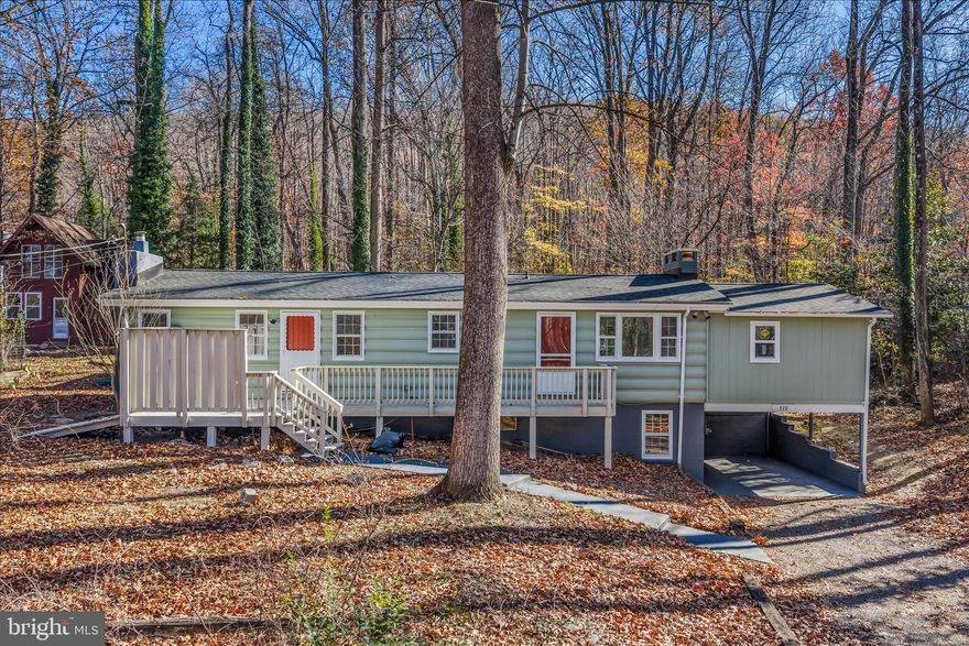 This 3 bedroom 2 bath cabin has been completed renovated. In addition to the lovely cosmetic updates you will have a new roof, new gutters, new electrical upgrade, and a new septic system - WOW! You have central AC, minisplit, 90+ gas furnace and 200 amp electric service. This home sits on a wooded 0.633 acre lot and is made up of 3 buildings. The home features a large front deck. This is the perfect place to enjoy the surrounding nature and host all your summer get togethers. Inside the home, you have a large dining room with LVP floors, vaulted ceiling with accent beams and ceiling fan. The wood burning fireplace features a raised hearth and heatolator with airtight wood stove insert. The dining room opens to the kitchen. LVP floors carry through. Your kitchen features new stainless steel appliances and a disposal. The sage cabinets provide ample storage and are beautifully accented by granite countertops. Beyond the kitchen you have a nice laundry room with cabinet storage, washer and dryer convey.  The living room measures 14 ft x 20 ft. Here you have LVP floors and lots of windows for natural light. You'll enjoy cozying up to the woodburning fireplace with glass doors in the coming months. Down the hall you have 2 generously sized bedrooms with carpet, vaulted ceilings with fan, and plenty of storage space. Bedroom 3 includes the added bonus of built-in shelving. The hall bath features a 5 ft porcelain on steel tub/shower, LVP floors, and single bowl vanity for plenty of storage. The primary suite is a space you will adore. The bedroom is carpeted and features vaulted ceilings and tons of natural light. Your private ensuite features LVT floors and 4 ft acrylic shower. You'll have plenty of storage between the shelving and double bowl vanity. Speaking of storage, the suite is topped off by a huge walk-in closet. The lower level of the home is finished into a 13 ft x 19 ft family room. The space features LVP floors, tons of natural light, and the home's 3rd woodburning fireplace. Just imagine how great this space will be when you're hosting the upcoming holidays! The family room walks out to the carport, great for keeping you and your car out of the weather. The rear yard features mostly level land with tons of mature trees. This affords excellent privacy from neighbors, even in these leafless months. The yard also includes your 2 bonus structures. There is a green storage shed with concrete floors and lots of shelving. The red building is a large workshop with a walkup loft. It is wired but needs to be connected to the main line. With water hookup and a little work this would make a great in-law suite of income unit. This home has the space you need, the privacy you crave, and two bonus buildings. Don't wait on this one - schedule you're showing today!