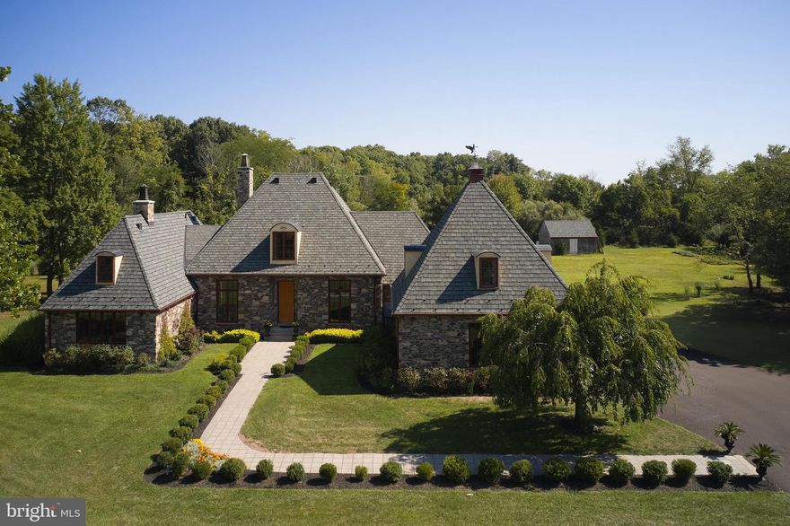 Within the peaceful countryside of Tinicum Township, is Barnstone, a stone manor house that reflects the architectural aesthetic of French country at its best. Designed by architect Jack Arnold of Homes of Elegance, this luxury home was crafted for graceful living. Built of stone from a 150-year-old barn that once stood on the original farmstead, the home has a recent roof with a transferable 50-year warranty. 
The interior of the home has a logical floor plan that moves from the front foyer to the ample-sized dining room on the right and then straight back to the oversized Great Room, which has a wood-burning fireplace, extra wide crown moldings and a bar with wine refrigeration. A wall of glass doors is ideal for displaying the large entertainment patio beyond the open yard. The eat-in kitchen contains Ukrainian blue mica granite countertops, custom cabinetry and a chef's appliance package. There is a large pantry, powder room, and staircase to the au pair bedroom.
The main floor contains a reading nook overlooking the front lawn and the primary bedroom with a sumptuous bathroom. Just down the hall is the den/library for your entertainment and a second powder room is sensibly located.
The second floor has two family or guest bedrooms with two bathrooms.
The large basement is ready to be converted to a theater room, gym, or whatever your imagination conjures.
Barnstone is a refreshing change from the typical center hall colonial that is so plentiful in today’s market. Let your vision drift to the French countryside which will prepare you for an invigorating visit.   Within walking distance of Tinicum Park pickle ball, basketball and tennis courts and park swimming pool and hiking trails.