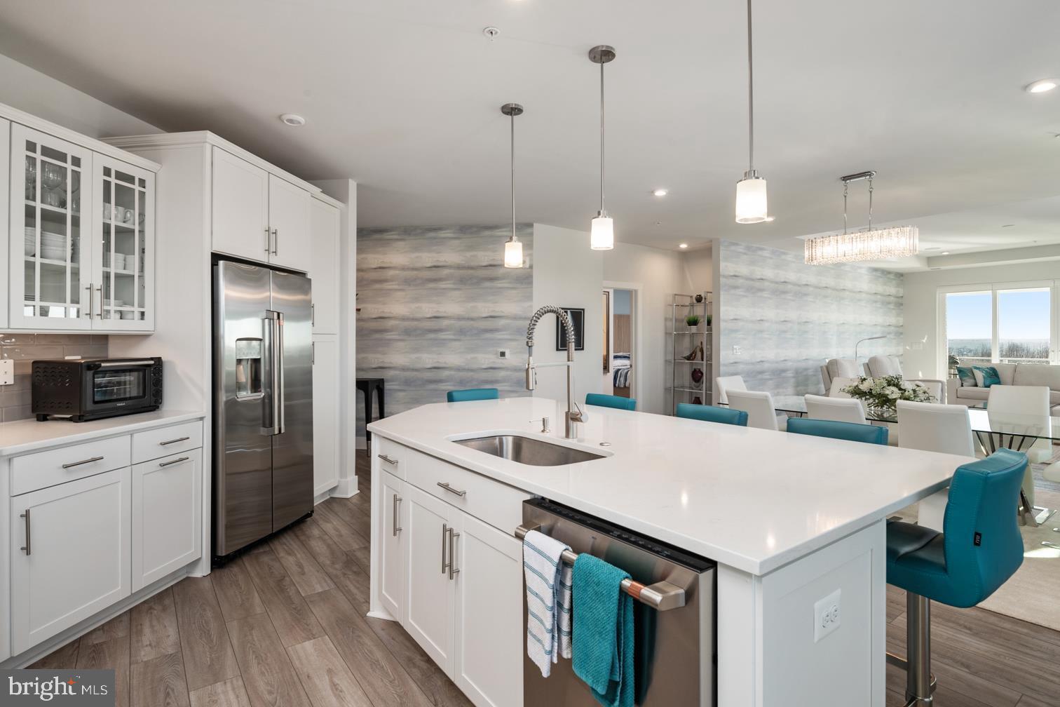 Four Seasons at Kent Island is an active 55+ community on Maryland's Eastern Shore, offering island resort-style & maintenance-free living at its finest! This Severn model is a spacious and airy 3 bedroom, 2.5 bath penthouse, end-unit boasting an expansive open floor plan with over 2600 square feet of luxurious living space. This home features a lavish gourmet kitchen and dining area, a huge great room with sliding door access to a large corner balcony.
As you enter this home through an inviting foyer you have direct access through French doors to a home office/guest bedroom.
The distinguishing features of this home include a state-of-the-art kitchen equipped with GE Energy Star stainless steel appliances, multi-functional range top with a Wi-Fi Connect Enabled hood, upgraded quartz countertops, oversized center island with pendant lighting, upgraded staggered custom cabinets with slide out drawers and brushed nickel hardware. Whether you’re preparing a quiet meal for two or hosting a lively gathering, this kitchen is as functional as it is beautiful.
The homes’ dining and living areas extend from the kitchen with an open, yet intimate layout, bordered with oversized windows allowing for lots of natural light. Levolor Cellular Shades provide light control and privacy, when needed. A very special feature is the Surround Sound Home Theater with an 85 inch flat screen TV. The entire home theater will be yours to enjoy.
The fantastic owner's suite boasts a decorative wall mounted designer panel, has an adjoining sitting room with access to the balcony, an owner's spa bath and 2 oversized walk-in closets.
Two large secondary bedrooms are located in a separate wing of the home and each feature a walk-in closet and share a Jack and Jill bath. This section of the home has a separate laundry room with built-in cabinets and a GE SMART washer and dryer.
Special features throughout the home include custom closets by Closet America, Candice Olson wallpaper, black-out blinds in all bedrooms, remote control blinds on slider leading to balcony, and tray ceilings throughout the home - a benefit of being a penthouse unit. Quartz countertops and luxury ceramic tile are included in all baths.
This home also has the LARGEST garage in the building, and the LARGEST storage room in the building, which is a few short steps from the elevator.
This MUST SEE condominium is ready for immediate delivery and shows better than a model, better than new – the thought, planning and design that have gone into this home is second to none!
KEEP IN MIND THIS SEVERN MODEL, WITH OVER 2600 SQUARE FEET OF LUXURY LIVING SPACE, IS AVAILABLE TO YOU NOW. PRESENTLY, THERE IS A 7-10 MONTH WAIT FOR THE COMPLETION OF NEWLY CONSTRUCTED SEVERN MODELS, BUT THIS UNIT IS MOVE-IN READY WITH PLENTY OF HIGH-END DESIGNER FEATURES AND UPGRADES ALREADY INCLUDED. Award winning 24,000 Square Foot Clubhouse with Stunning Chester River Views! Fantastic amenities include an infinity pool, indoor pool with, fitness center, library, game room, fire pits, tiki bar equipped with refrigerators, sinks and television monitors, pier with transient boat slips, walking paths that link to the Cross Island Trail, pickleball & tennis courts, bocce, dog park, and an outdoor amphitheater for live music and movie nights. The community lifestyle director will keep you busy with daily activities such as yoga, a variety of exercise classes and an assortment of clubs including biking, billiards, book club, baking, mahjong, environmental club, trivia night and more. In addition to the weekly and monthly activities, residents can enjoy crab feasts, and holiday gatherings throughout the year. This development is an unrivaled, amenity-filled, resort-style experience with convenient access to Annapolis, DC, Baltimore, and BWI. Kent Island offers multiple dining and shopping options, a nearby outlet mall, and a 6.5 mile cross-island trail surrounded by views of the Chester River.
