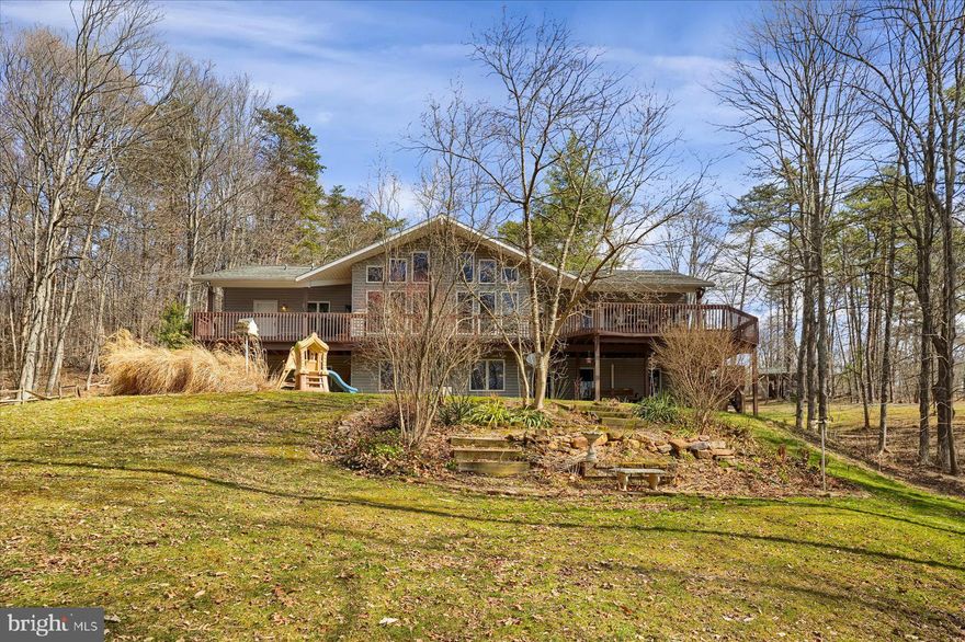 Nestled on 14 private acres, this spacious 4-bedroom, 4-bath home blends comfort with breathtaking natural surroundings. Inside, an open and airy floor plan is bathed in natural light, creating a warm and inviting atmosphere. The well-appointed kitchen features ample cabinetry, granite countertops, stainless steel appliances, and a large counter space ideal for cooking and gathering. The adjoining dining area flows seamlessly into the living room, where large windows frame the scenic views. The primary suite is a true retreat, complete with a private bath and access to outdoor living spaces. A bright sunroom offers the perfect spot to relax with morning coffee, while the finished lower level features a family room, two additional bedrooms and two full bathrooms. Step outside to enjoy the expansive deck, where you can take in the peaceful wooded surroundings. Whether you’re exploring the trails, gathering around the fire, or simply unwinding in nature, this property offers endless opportunities for outdoor living all within easy reach of State College, Huntingdon, and Raystown Lake.