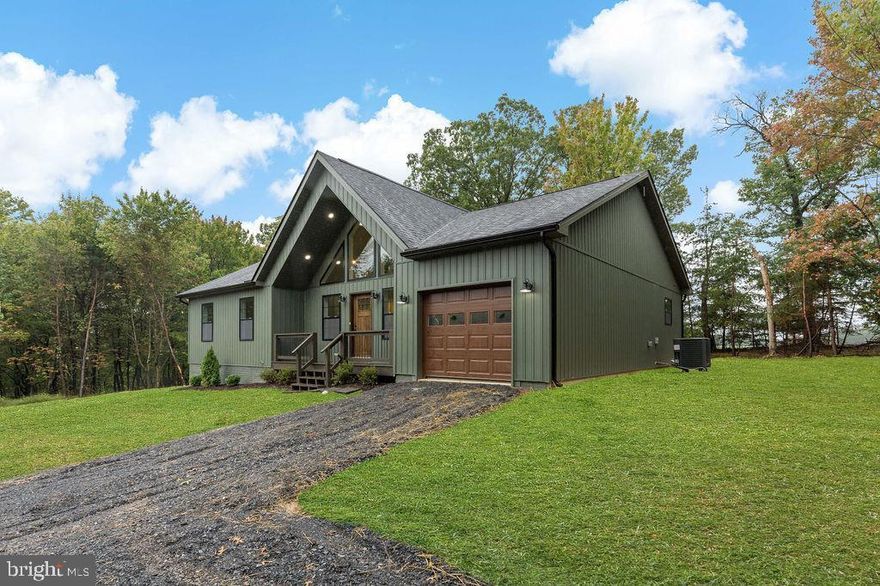 The front of the home features sleek Black windows and Board & Batten siding . Step inside and you'll be met with beautiful luxury vinyl plank flooring, vaulted ceilings with beams -stained to your color choice, gas fireplace, stainless steel kitchen appliance, LED remote controls customize lighting in the living room with recess lighting in the open floor plan, walk-in closet in primary bedroom , mud room equipped with washer & dryer and mudroom sink, & so much more.. 1,800 sq ft finished all luxury vinyl plank flooring, and an additional 1,800 sq ft unfinished, plus a mudroom off the garage, this home offers both style and functionality. Schedule a showing to make this home yours!This mountain style house is a two minute drive to CACAPON STATE PARK & 10 miles from downtown Berkeley Springs. ***Pictures are of similar construction