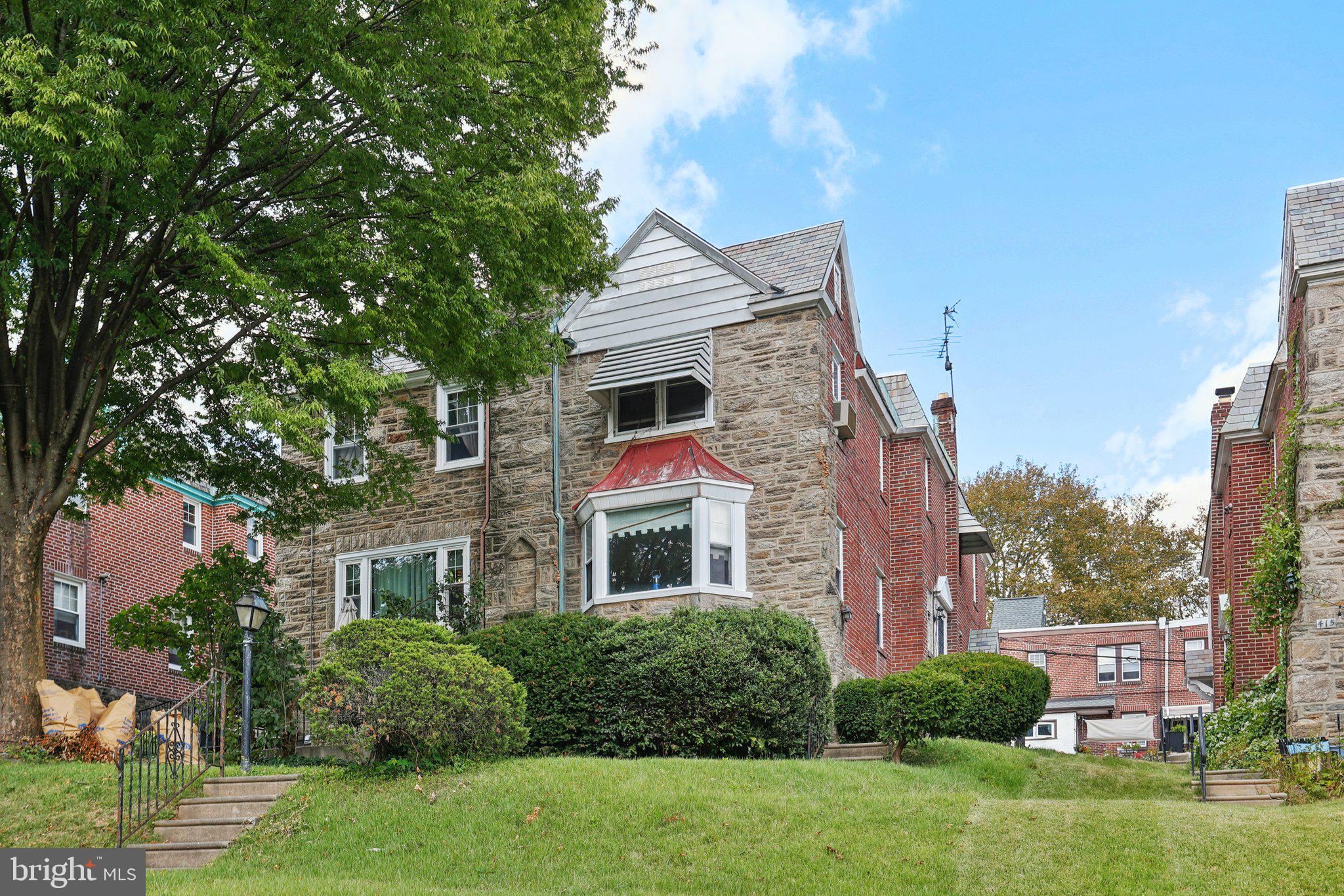 Welcome to this charming and spacious stone and brick twin home nestled in West Mt. Airy with tons of potential! From the moment you arrive, you'll be drawn in by the large front yard, a quaint front patio, and a private walkway that invites you into the main level with tons of character. Enter inside through the welcoming foyer, where a tucked-away half bath offers convenience for guests. The light-filled front living room features two large windows and a lovely bay window, bathing the space in natural light. The formal dining room also boasts generous sunlight and opens right into the kitchen complete with a cozy breakfast nook featuring a charming built-in. A side door provides access to the walkway, making it easy to reach both the front and rear of the property. Upstairs, you’ll find three generously sized bedrooms. The primary features a graceful arched entryway, ample closet space, and a private ensuite bath. The two additional bedrooms are equally spacious, sharing a full hall bath. The rear bedroom features a unique arched entry into his-and-her closets. The full basement offers even more living space with a large recreation room complete with a built-in bar. You'll also find a half bath and laundry room. The basement door exits to the one-car garage and rear driveway. Located just minutes from shops, restaurants, parks, and public transportation, it offers the best of city living with a neighborhood feel. Mortgage savings may be available for buyers of this listing.