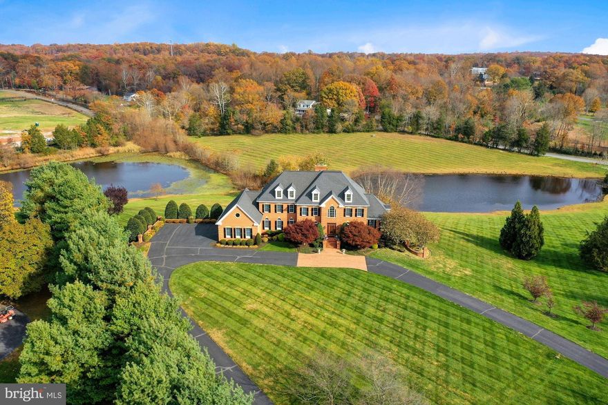 Welcome to this exquisite, all brick, estate home in the highly desired and coveted neighborhood of Barclay Ridge. This meticulous home sits on 3+ majestic acres with two ponds and mountain views as far as the eye can see... a peaceful retreat like no other! Outstanding features of this stunning home include a tree lined, circular driveway; oversized three-car side-load garage; hardwood floors throughout the main level; exquisite mouldings throughout; three cozy fireplaces (one that is gas and two that are a hybrid of gas or wood burning); light-filled Sun Room with vaulted, beamed ceilings; a main level Study/Home Office with built-in shelving; sunken Family Room with stone fireplace and two accesses to the expansive deck; a Kitchen perfect for Entertaining with a true walk-in pantry, island, granite counters, cherry cabinets, and Breakfast Room; Primary Suite with French door entry, Tray ceilings, cozy Sitting Room, walk-in closet , EnSuite Bath with soaking tub, dual vanities and walk-in shower; the upper level also hosts three additional Bedrooms each serviced by their own private Bathroom; fully finished lower level walks out to the rear, covered patio and boasts a Rec Room with stone fireplace, a Billiard/Game Room, a Library/Lounge, a full Bathroom, and a Bonus Room that could be used as an Office, Den or Play Room; incredible outdoor entertaining spaces, which include a deck that spans the length of the home and a covered patio - both of which overlook the two ponds and tree lined mountains.  Located just a short drive to downtown Leesburg, Loudoun County Wine and Hunt Country, shopping at the Leesburg Outlets/One Loudoun/Brambleton Town Center, access to commuter routes (Dulles Green Way, Dulles Toll Road, Routes 50/7/28) and minutes to Dulles Airport, and so much more. This absolutely breathtaking property is waiting for you to call it your new home!
