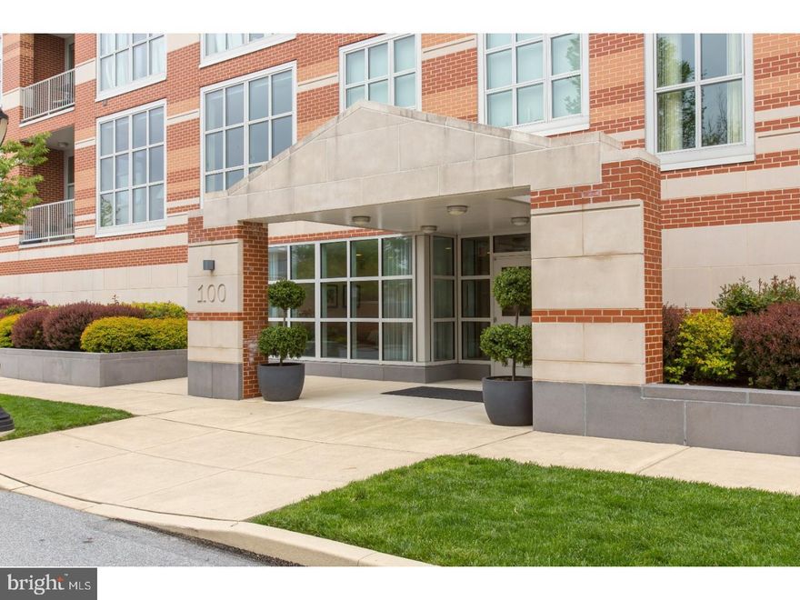 Welcome to 123 Iron Works Way—an impeccably maintained one-bedroom, 1.5-bath luxury condo in the heart of vibrant downtown Wayne. Soaring 10-foot ceilings and expansive wall-to-wall windows flood the living space with natural light while showcasing dynamic town views. The open-concept floor plan offers flexibility to suit a variety of lifestyles, seamlessly blending the living and dining areas with a stunning, oversized island kitchen. Designed for both everyday living and entertaining, the kitchen features elegant cabinetry, GE Monogram appliances, and granite countertops. Step outside to your private balcony—an ideal spot to unwind and take in the energy of this sought-after location. The spacious bedroom suite serves as a serene retreat, complete with sweeping views, remote-controlled custom shades, a generous size dressing area with custom closets, and a luxurious en-suite bath featuring a double vanity, soaking tub, and frameless glass shower. A versatile den/office off the main hall provides the perfect work-from-home space or can easily function as a guest room. Additional highlights include a convenient laundry area with a newer washer and dryer. This exceptional residence also includes one assigned parking space and two climate-controlled storage lockers (#6 & #12), conveniently located inside the garage. Designed by renowned architects, Pembroke North is a standout building known for its quality and sustainability. The property proudly holds LEED Gold certification and offers energy-efficient features such as geothermal heating and cooling.  Enjoy unparalleled walkability to downtown Wayne’s shops and restaurants, along with easy access to the St. Davids and Wayne train stations and major highways. Professional photos coming soon.