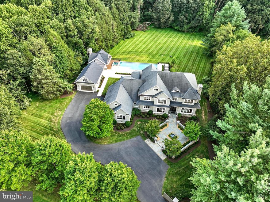 Luxury Resort-Style Living in Great Falls

Set on more than two acres of pristine grounds, this custom estate by Ted Visnic, National Association of Home Builders Custom Home Builder of the Year (2011), blends timeless architecture with modern innovation. More than $1.5M in upgrades—including significant contributions by Pristine Acres and Hannah Charlotte Interiors—have elevated the residence into a resort-style retreat.

Across three levels, the home offers five bedrooms, five full baths, and three half baths. A gated drive leads to a stone façade and entry courtyard, opening to interiors finished with bespoke millwork, Portola limewash walls, grasscloth wall coverings, solid bronze and alabaster fixtures, Hunter Douglas window treatments, and layered custom textiles. Every room has been thoughtfully curated, from the sitting room painted in Portola Lone Cypress with Rockville Interiors drapery and Allied Maker sconces, to the library with lime wash walls, custom millwork, Shane Britain sconces, and a cut-and-bound wool rug. The formal dining room is wrapped in grasscloth wallpaper and anchored by an Urban Electric chandelier, flowing into a butler’s pantry and chef’s kitchen. Here, dual painted islands and professional-grade appliances are complemented by a light-filled breakfast area overlooking the spectacular backyard and pool. The main level continues with a handsome library, a dramatic great room with tongue-and-groove ceiling and stone fireplace, and additional spaces including a mudroom, laundry room, and four-car garage.

Upstairs, the primary suite features a private terrace with views over the pool and pool house, a marble-clad bath with dual vanities and a walk-in glass shower, and a boutique-style walk in closet. Each secondary bedroom is complete with its own en-suite bath and walk-in closet. The lower level extends the living space with a recreation lounge anchored by a fireplace and wet bar, a media room, mirrored fitness studio, and a private bedroom suite and bonus room. Newly replaced flooring, stair runners, a central vacuum system, and UV window protection add comfort and convenience.

The backyard is where the estate becomes a private resort. Designed by Pristine Acres, the heated saltwater and chlorine pool includes an automatic cover, custom lighting, and a spa with waterfall edge that flows seamlessly into the pool. Expansive stone terraces, manicured lawns, irrigation, and upgraded exterior lighting create a series of outdoor entertaining areas. The fully outfitted pool house includes an outdoor kitchen, stone fireplace, full bathroom with shower, and motorized retractable screens, offering the perfect year-round entertaining space.

Modern systems and technology complete the property. The home is equipped with Control4 smart automation by Theatron, whole-home lighting and sound, new HVAC systems, new tankless water heaters, and a UV water purification system. A gated entry with upgraded cameras ensures security, while both the main house and pool house are backed by a generator for peace of mind. The grounds are meticulously maintained by Independence Landscaping, ensuring the estate’s outdoor spaces remain as pristine as its design.

Additional enhancements include custom office built-ins, refinished walnut floors, invisible fencing, and a repaved and extended driveway.

This is a rare offering in Great Falls, where craftsmanship, design, and technology converge with resort-inspired amenities to create a lifestyle of unmatched quality and comfort.