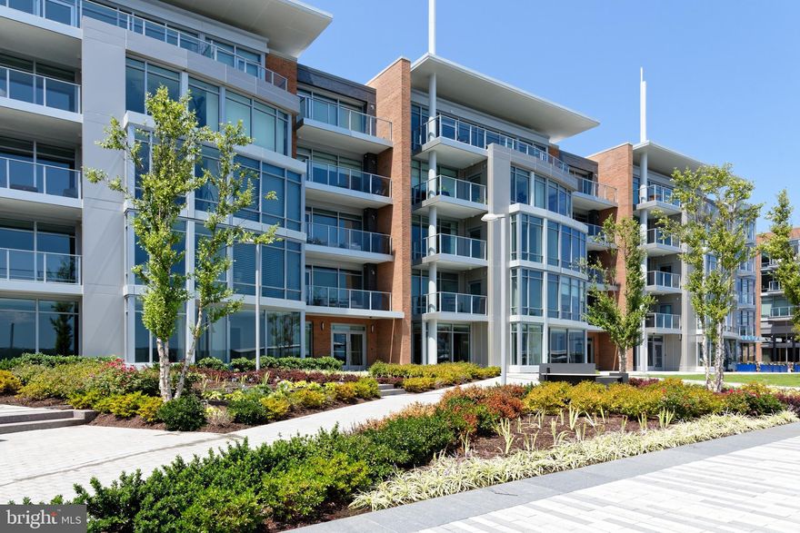 Remarkable corner residence with  views of the Potomac River and Old Town rooftops, slightly reminiscent of London, but in the heart of Old Town Alexandria at Robinson Landing.   Tall windows wrap around the living and entertaining space as well as the chef's kitchen.  Enjoy exceptional water vistas from the private balcony and barbecue on the new Fuego gas grill.   A small desk area with bookshelves provides a computer workspace off to the side.    Natural light floods in through south facing oversized multipaned windows, capturing both morning and afternoon light.  The kitchen is a chef's dream complete with gas cooking and top-of-the-line Thermador appliances including two individual refrigerator drawers.   Frameless European styled cabinetry and quartz countertops with waterfall island add to the attention to detail.  The long, free standing island with waterfall edges allows ample space for bar stools.   A generous master bedroom with wood floors and linen shades on wide windows offers a custom walk-in closet plus two additional closets, an oversized master bath with graceful soaking tub, seamless glass shower and floating twin vanities with lighted mirrors.  Guests will never want to leave their comfortable quarters with an inviting bedroom, sizeable closet and ensuite bath.   Two garage parking spaces right outside the elevator entrance are very convenient.  A storage unit also conveys.   This is sophisticated living in an exciting new waterfront community with amenities including a fitness center, pet grooming spa, bike room, concierge service, and two exceptional restaurants on the river promenade, just steps away from your front door.