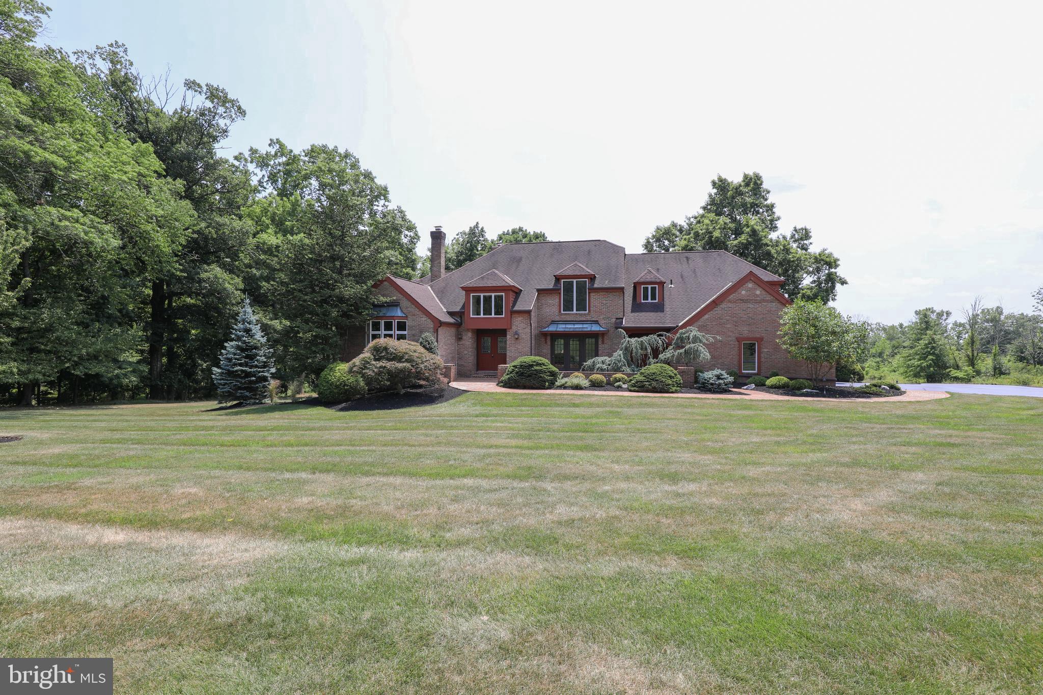 There aren't many opportunities like this....an incredibly private setting on 11 acres with an estate home tucked off a quiet country road, and yet only 8 minutes to Doylestown's Boro.
A unique blend of styles, this four bedroom, three and a half bath custom home offers many one of a kind architectural features. When you step inside, you'll discover spacious living areas, abundant natural light and hardwood floors just about everywhere! The Living room showcases a 4-panel bow window, vaulted ceilings and a wood burning fireplace. The ample sized Dining room offers coffered ceilings, vintage silk wallpaper and triple French doors which leads you to a hidden garden. Traveling to the back of the home, you'll find a Family room with vaulted ceilings, floor to ceiling brick fireplace with custom cabinetry and a wall of French/Atrium doors that spill out to the multi-level composite deck, with views of the backyard, pool and the woods beyond. The Kitchen is off one end of the Family room , creating an easy flow for entertaining as well as everyday Life. This Kitchen provides great workspaces, lots of cabinetry and counterspace as well as a second sink. The "Breakfast room" has an abundance of windows which overlooks the deck, pool and backyard. A first floor Primary suite, located at the other end of the home, offers a gracious space with more vaulted ceilings, a floor to ceiling brick feature, en suite primary Bath, two walk-in closets, more windows overlooking the backyard, and a Loft...could be a home office, library, exercise area, yoga or art studio etc. A well placed half Bath and a main floor Laundry (located as you enter from the 3 car garage, near the Kitchen) completes the first floor. The second floor offers two generously sized Bedrooms (one of which has an en suite Bath) as well as a secondary primary Bedroom and ensuite Bath with a walk-in closet. All Bedrooms have hardwood floors and enjoy fantastic views of the property. An oversized finished walk out Basement has an open floor plan and offers endless possibilities, and with a full Kitchen and a wood burning pizza oven, there's opportunities for some serious fun! There's also two storage/Utility rooms offering great storage.
Outside you’ll find an inviting pool, perfect for relaxing and/or entertaining. The expansive 11 acre grounds offer many options as some areas are wooded, some are open meadows and some are open yard space. From gardening to nature watching to recreational activities (bring a horse?), you'll enjoy the peace and quiet of country living with unmatched privacy. Centrally located to commuter roads and close to charming Doylestown Boro which offers cultural activities, restaurants, museums, festivals, shopping, the Court House, Doylestown Hospital and award-winning Central Bucks schools. Don’t miss this once in a lifetime opportunity to experience the lifestyle you’ve been dreaming of!