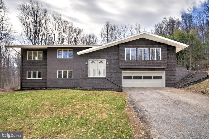 Welcome to a completely and beautifully renovated 4 bedroom, 2.5 bathroom single family home set on a peaceful one-acre lot in the desirable Frogtown area just outside Mechanicsburg! This property offers the perfect balance of quiet country living and easy access to major highways for commuting. The refreshed exterior immediately stands out with charming cedar shake accents and a welcoming double front door that creates attractive curb appeal. Inside, the bright and inviting main living area showcases beautifully refinished hardwood floors, abundant natural light, and a large brick fireplace that anchors the space and adds character. A door to the deck extends the living area outdoors, creating the perfect spot to relax or entertain while overlooking the private backyard. The huge brand new front-facing kitchen is truly the heart of the home, highlighted by a wall of windows that floods the space with light and makes it a place you'll love spending time in. It features a large center island ideal for dining and prep space, along with crisp white cabinetry, quartz countertops, stainless steel appliances, and thoughtfully upgraded finishes throughout. The bedroom wing offers three nicely sized bedrooms including a private primary suite with an attached bath featuring a walk-in tiled shower and double vanity, while the hall bathroom with a tub/shower combination comfortably serves the additional bedrooms. The lower level is an incredible bonus, offering a spacious second living area filled with natural light from walkout windows and sliding glass doors. A separate fourth bedroom is perfect for guests, a home office, or playroom. A convenient powder room and dedicated laundry room add to the functionality of this level. Major improvements include a brand new architectural shingle roof, efficient electric heat pump system, new water heater, and a fully inspected and passing septic system. With stylish updates, flexible living space, and a beautiful setting, this move-in ready home is an opportunity you won’t want to miss.