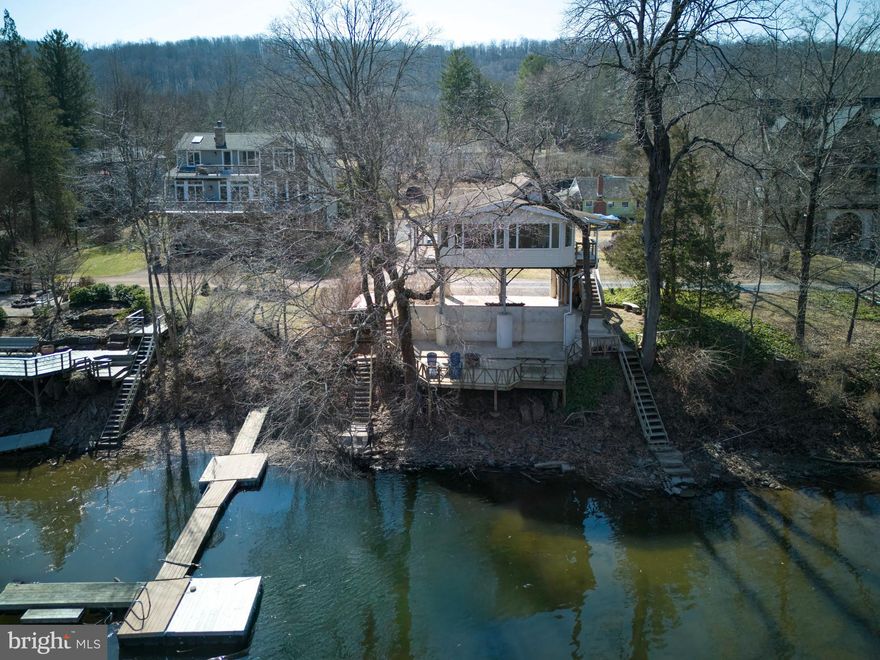 Along River Road in Upper Black Eddy, meandering private road takes you to Shad Landing, a quaint riverfront cottage. The cottage consists of two bedrooms, one bath. This elevated home is perfect for a weekend retreat, escape from the city or the perfect starter home. The home has been elevated with steel I-beams that create a security for the structure due to any future inclement weather.  The interior offers an open concept with a modern stainless steel kitchen, dining area, and living room. This room contains a wall of windows that looks out at one of the widest areas of the Delaware River. You can relax in the house and enjoy the lapping sound of the water below. There are two bedrooms that share a generous full bath. The home has an exterior covered area that can serve as parking or a front sitting area. The rear of the house has a large cement patio with a privacy wall-this area is perfect for alfresco dining, lounging or fishing. In the back, on one side, contains a set of stairs that leads to a future floating dock.  Shad Landing is an affordable gem set on a private, forgotten road that contains homes upwards of $2 million plus. Just 90 minutes from New York City or Center City, you can leave the craziness of today’s hectic world and be casting a line to catch this evening‘s dinner, all within 90 minutes.